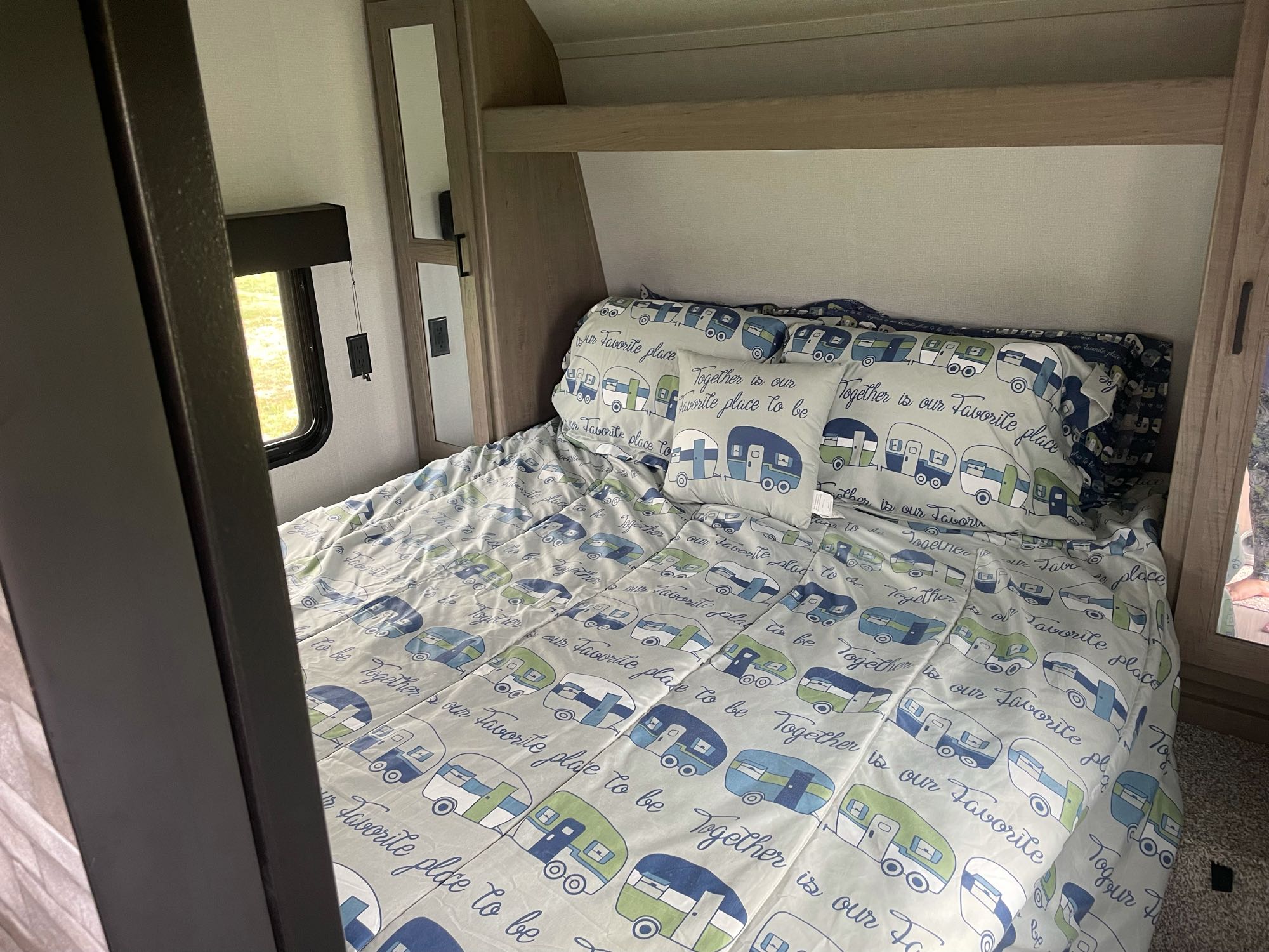 Cozy RV rental bedroom with a bed featuring light blue bedding, patterned with green/blue campers and a loving message.. Keystone Hideout 2021