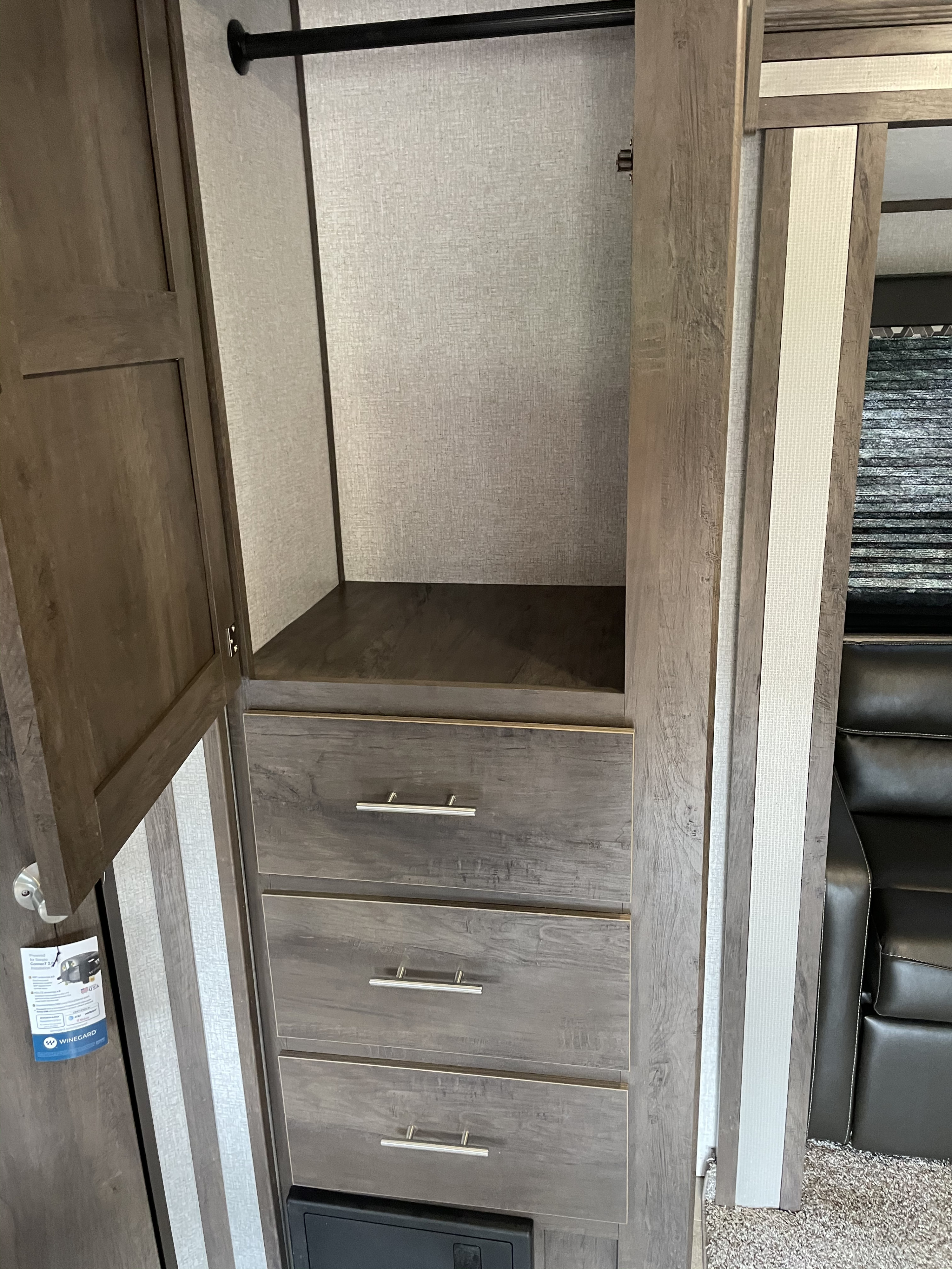 Inside an RV rental: a practical wardrobe with a hanging rod, shelf, and three wood-look drawers for organized storage.. Dutchmen Coleman 2021