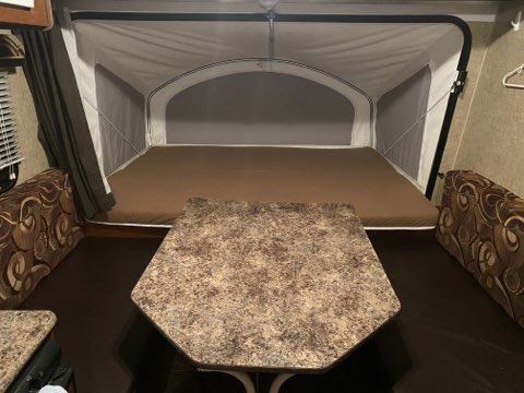 RV rental pop-up camper interior: large bed in rear expandable section, dinette with booth seating upfront.. K-Z Manufacturing Spree Escape 2014