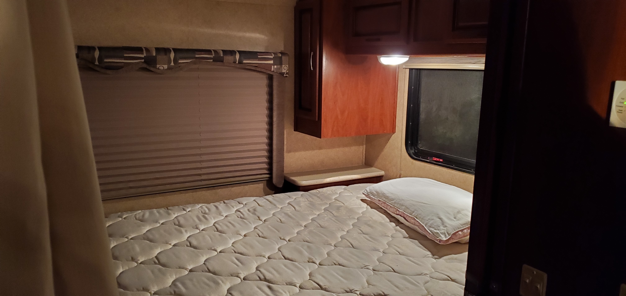 Experience comfort in this RV rental bedroom: quilted mattress, window with blinds, and storage cabinets. Ready for your trip!. Forest River Sunseeker 2011