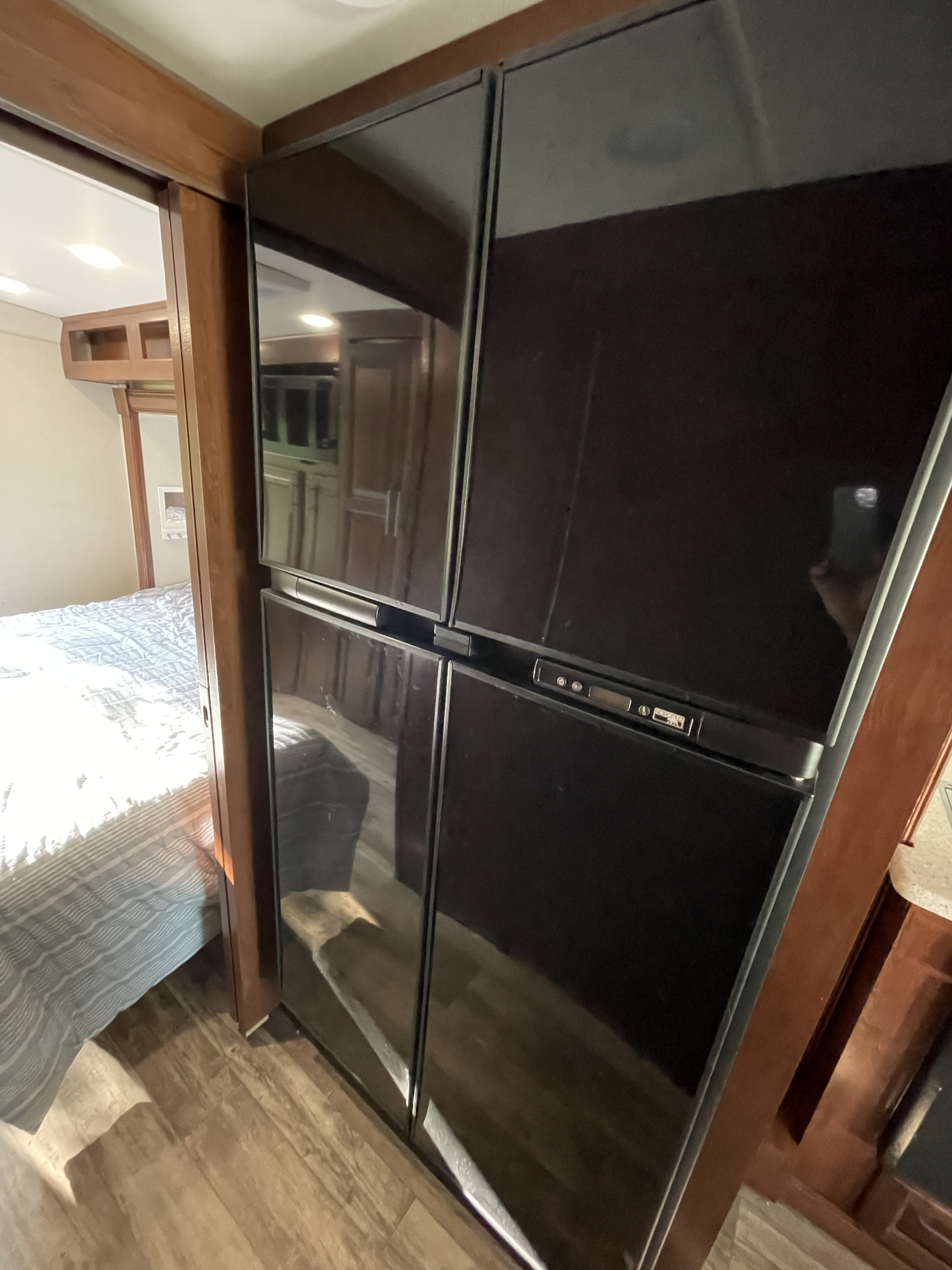 RV rental interior featuring a large black refrigerator and a glimpse into the bedroom with warm wood trim.. Forest River Forester 2018