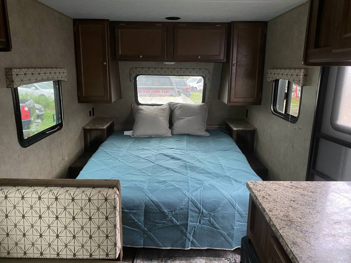 Explore this RV rental's inviting interior, featuring a cozy bedroom area with a bed, overhead storage, and countertop space.. Coachmen Other 2017
