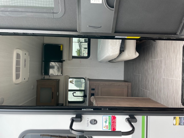 Compact RV rental interior featuring an AC unit, TV, small kitchen, and bed, viewed from the open doorway.. Forest River No Boundaries 2021
