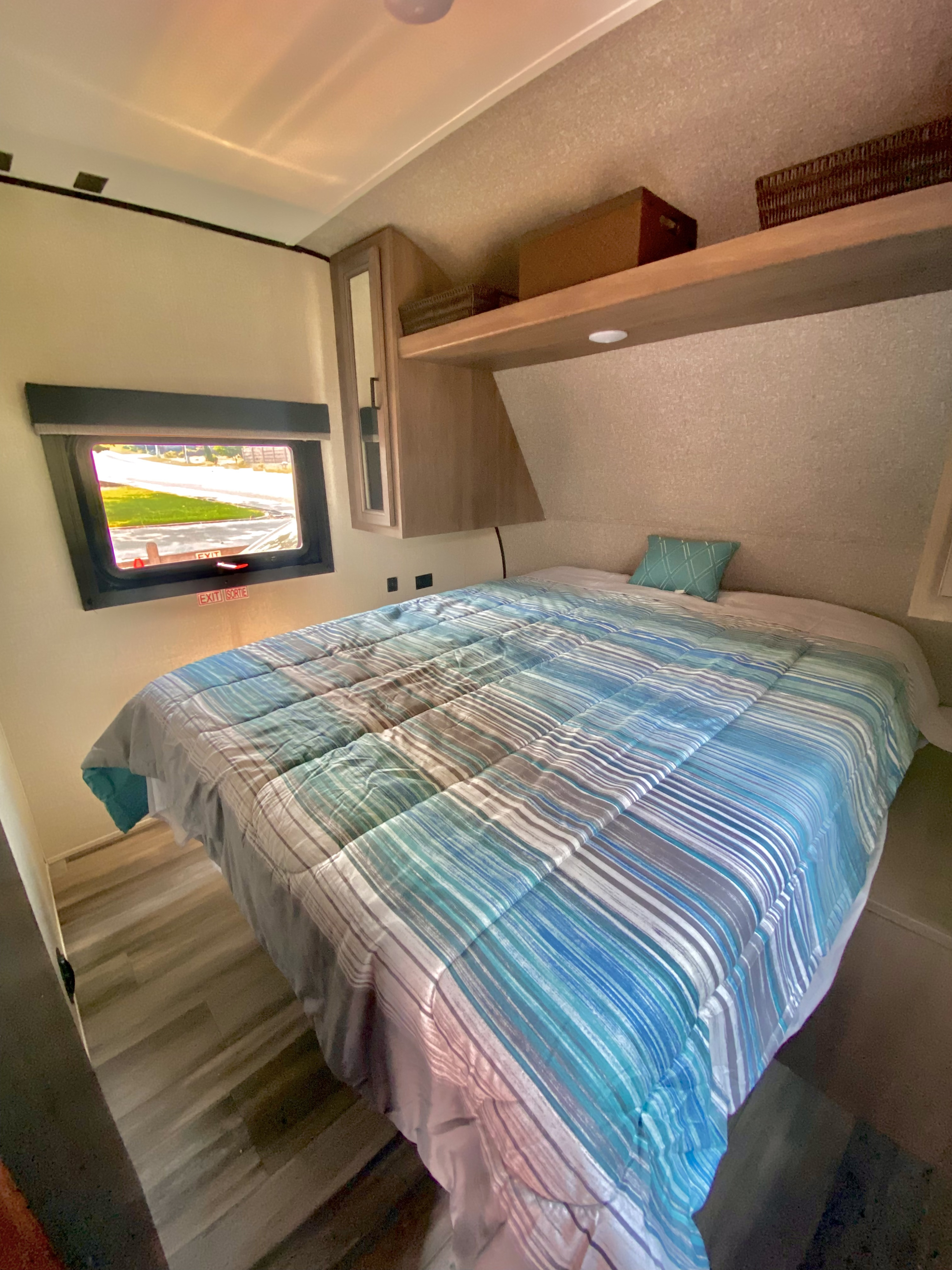 RV rental interior: comfortable bedroom with blue striped comforter, exit window & built-in storage.. Starcraft Autumn Ridge 2022
