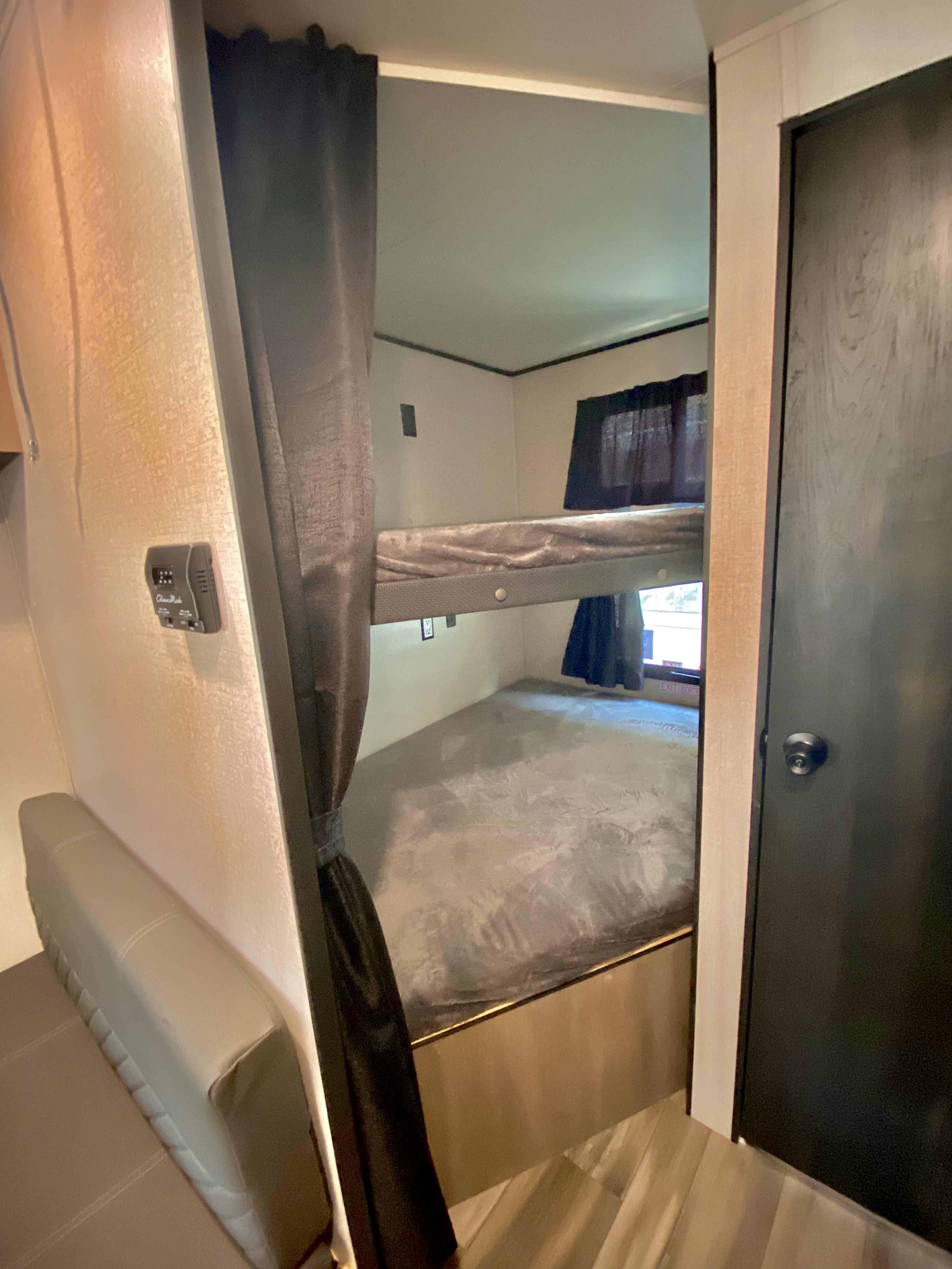 Compact RV rental interior featuring bunk beds, a sofa, and wall-mounted thermostat for comfortable stays.. Starcraft Autumn Ridge 2022