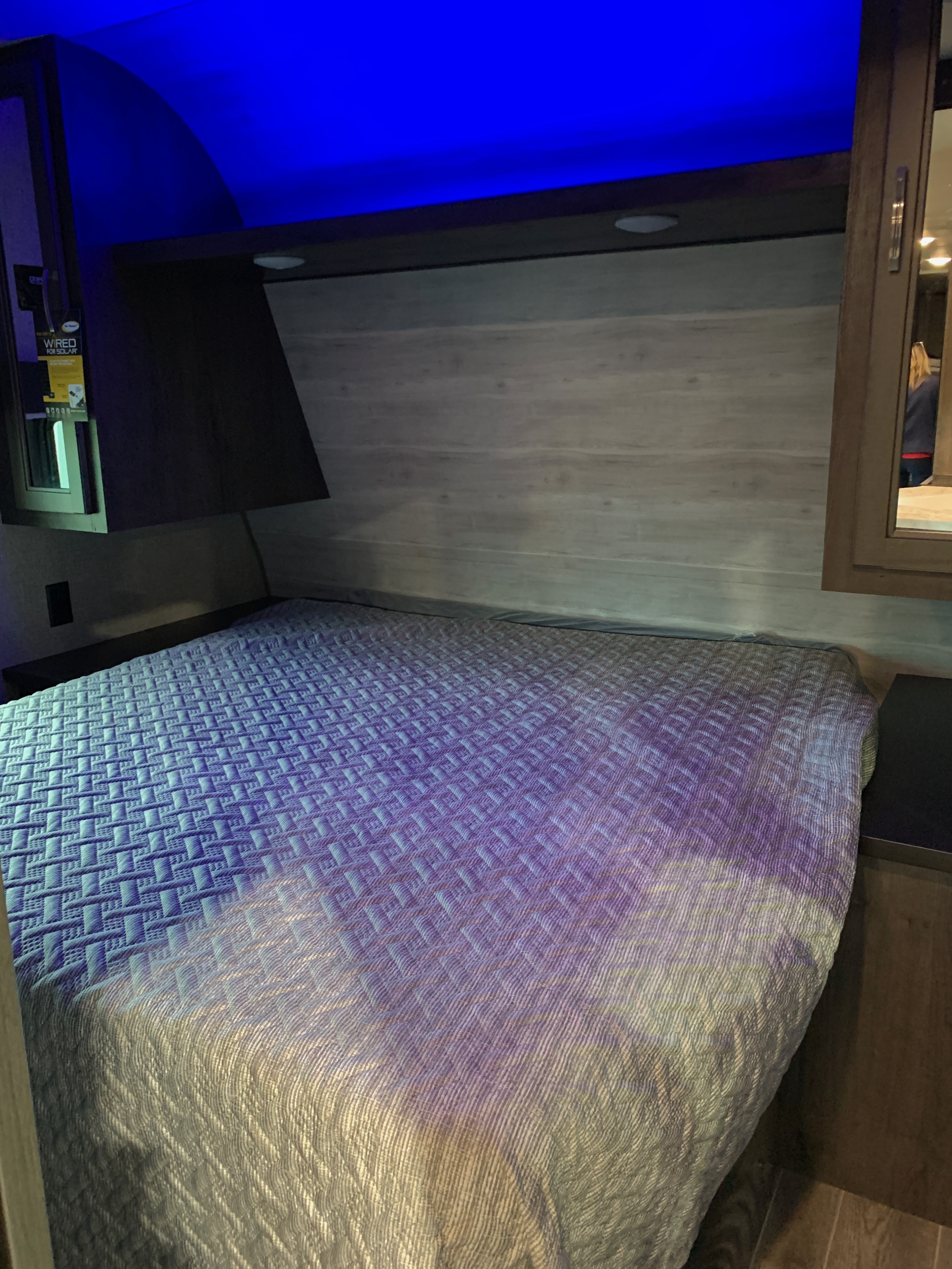 Cozy RV rental bedroom with a blue-lit ceiling, a textured bed, wood-paneled walls, and built-in storage. Ideal for travel.. Jayco Jay Flight 2021