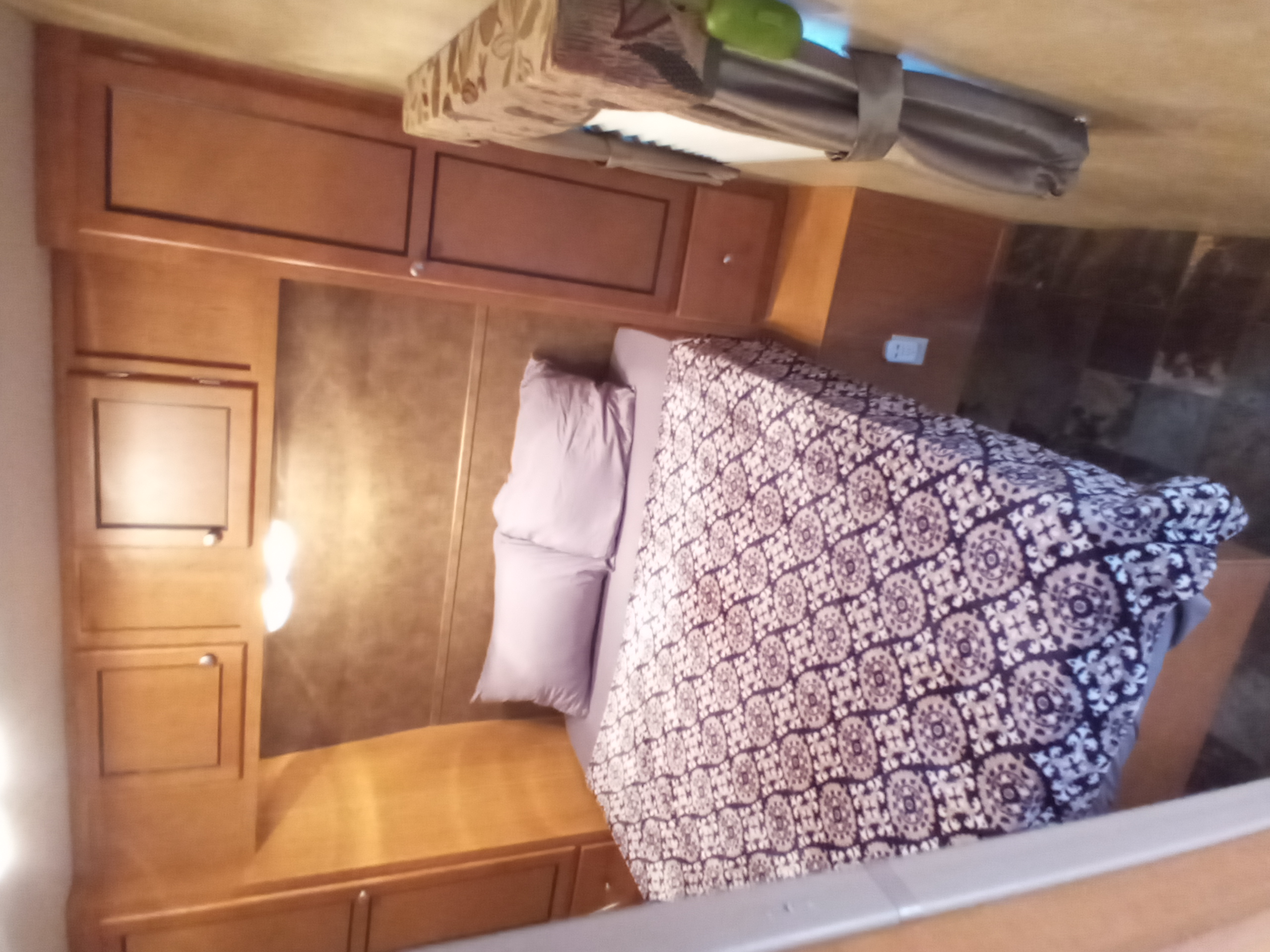 Cozy RV rental bedroom with light wood cabinets, patterned bedding, and ample storage.. Holiday rambler Traveler 2013
