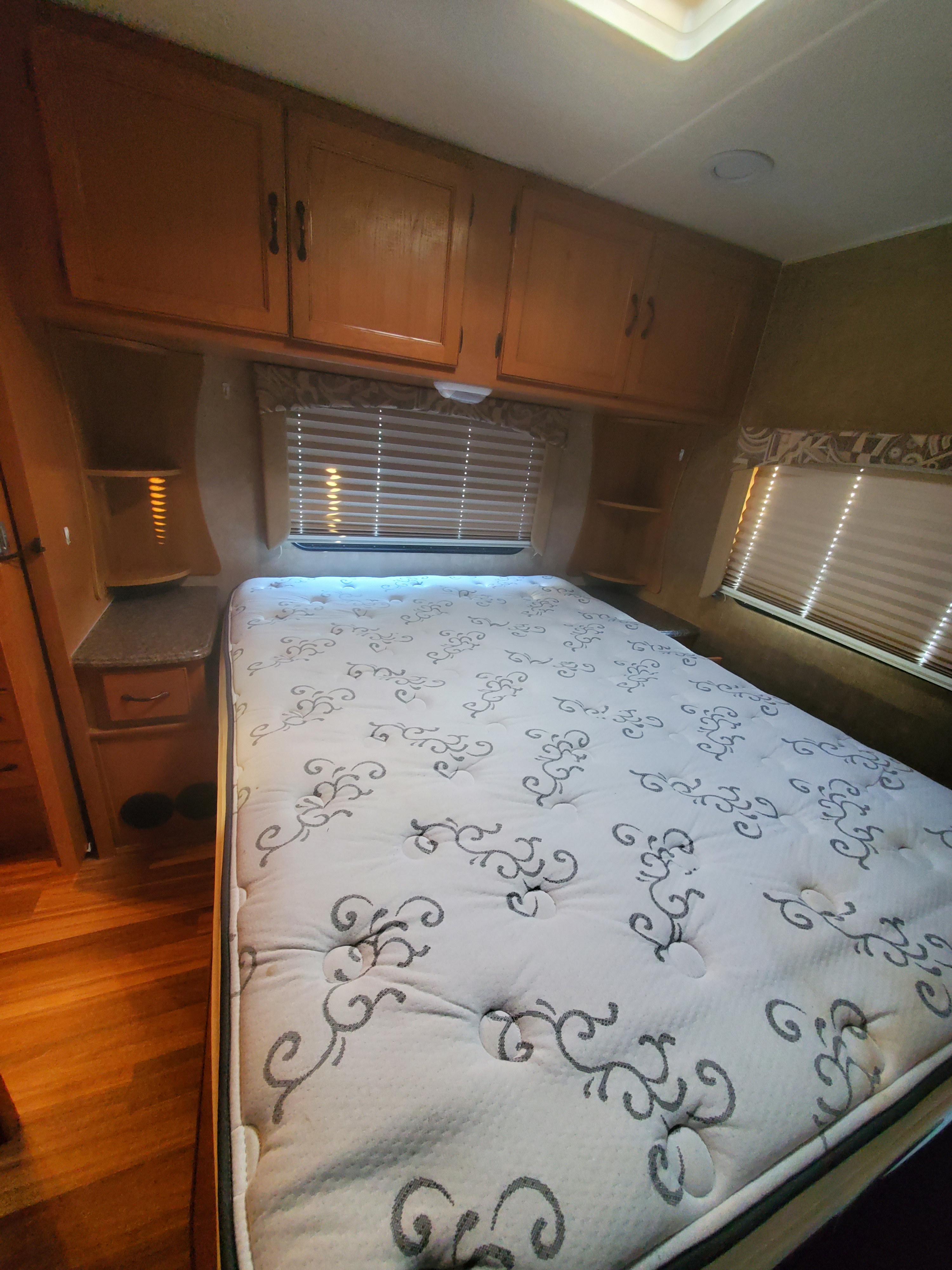 Comfortable RV rental bedroom with a queen mattress, overhead cabinets, and window blinds.. Other Other 2014
