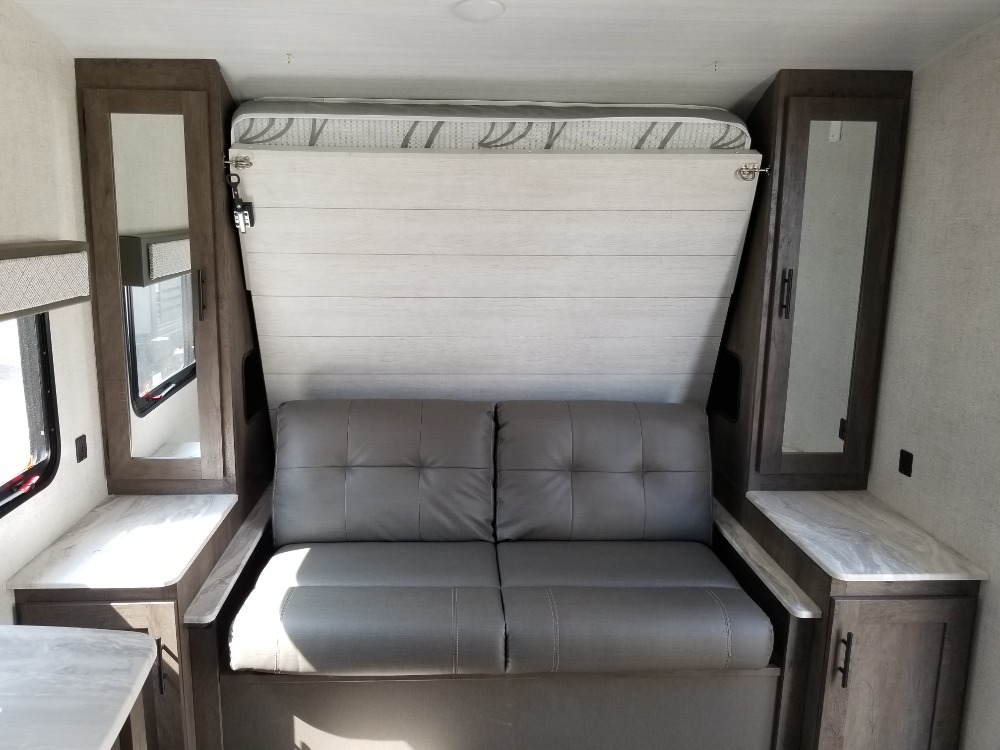 RV rental interior: a versatile space with a gray sofa, folded murphy bed, and mirrored storage cabinets.. Forest River Salem Cruise Lite 2021