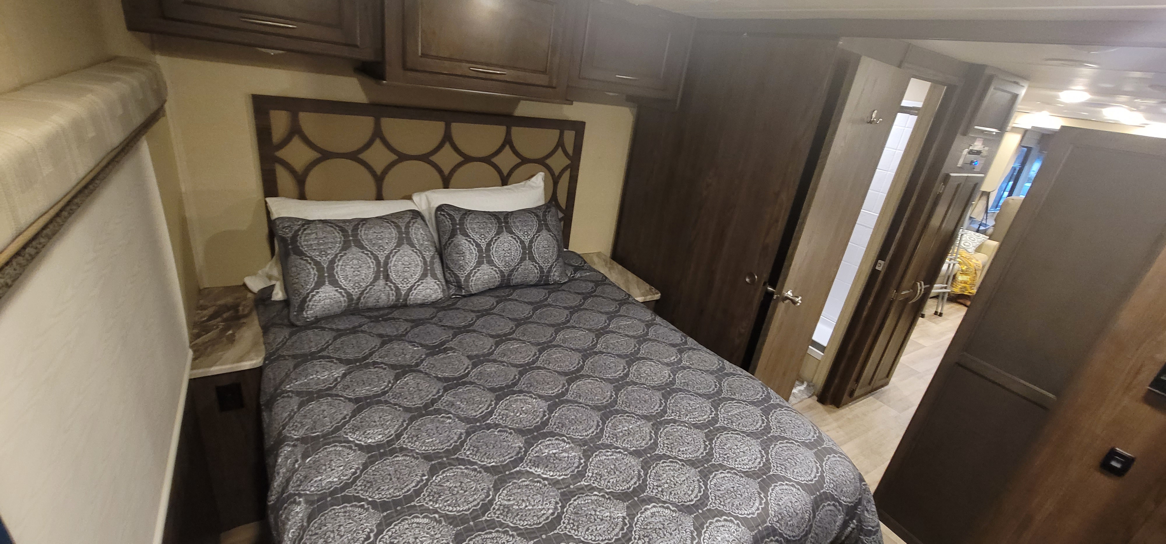 Inside an RV rental, this cozy bedroom features a patterned bed, a stylish headboard, and overhead storage. Perfect for road trips.. Coachmen Pursuit 2019