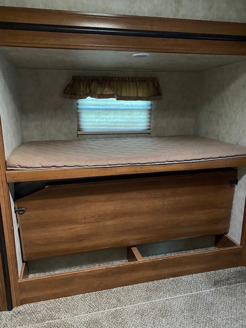 RV rental bunk bed features a comfy top mattress with window; lower section has a clever wooden panel for bed or storage.. Forest River Crusader BH 2015