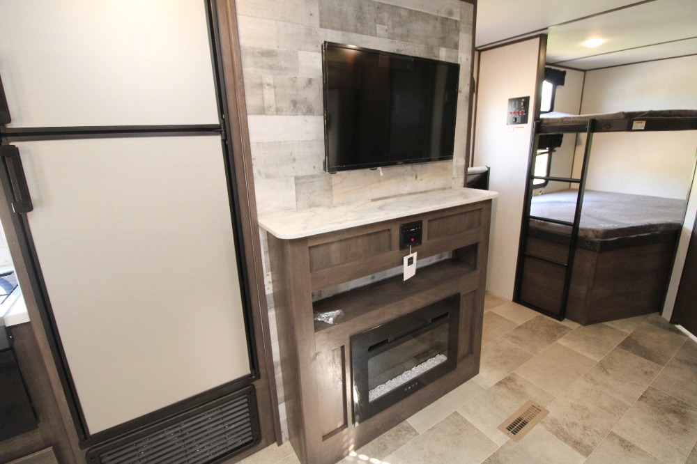 RV rental's inviting interior: full-size fridge, entertainment center with TV/fireplace, and cozy bunk beds.. Dutchmen Other 2021