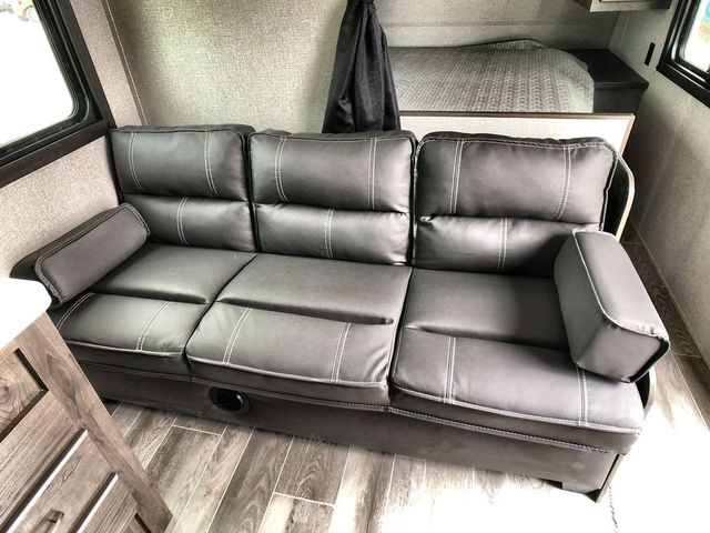 Inside an RV rental: a gray, three-seat sofa with white stitching, perfect for relaxing after a day's travel.. Jayco Flight 2021
