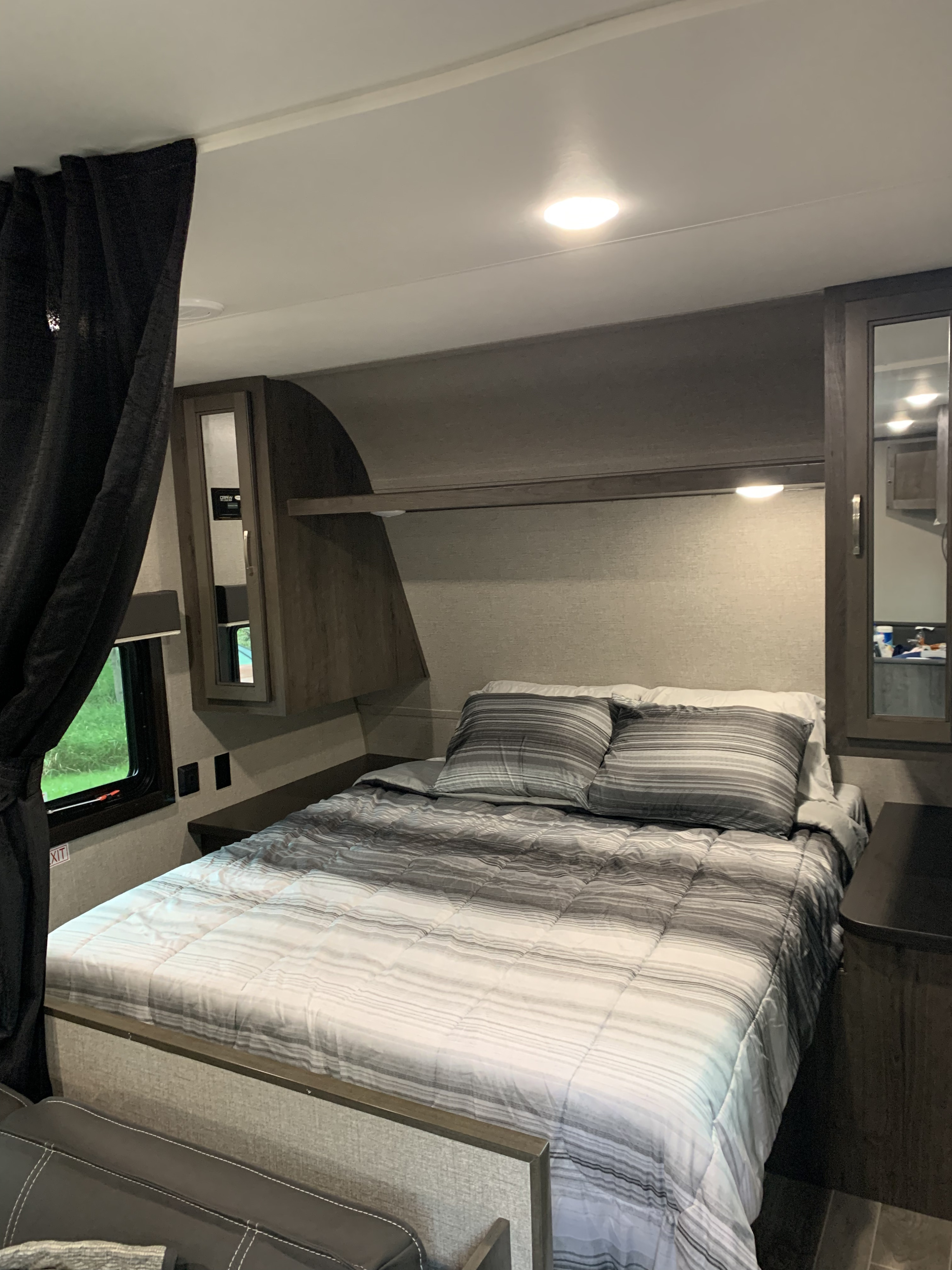 Cozy RV rental bedroom showcasing a striped bed, built-in storage, and window, designed for comfortable travel.. Jayco Flight 2021