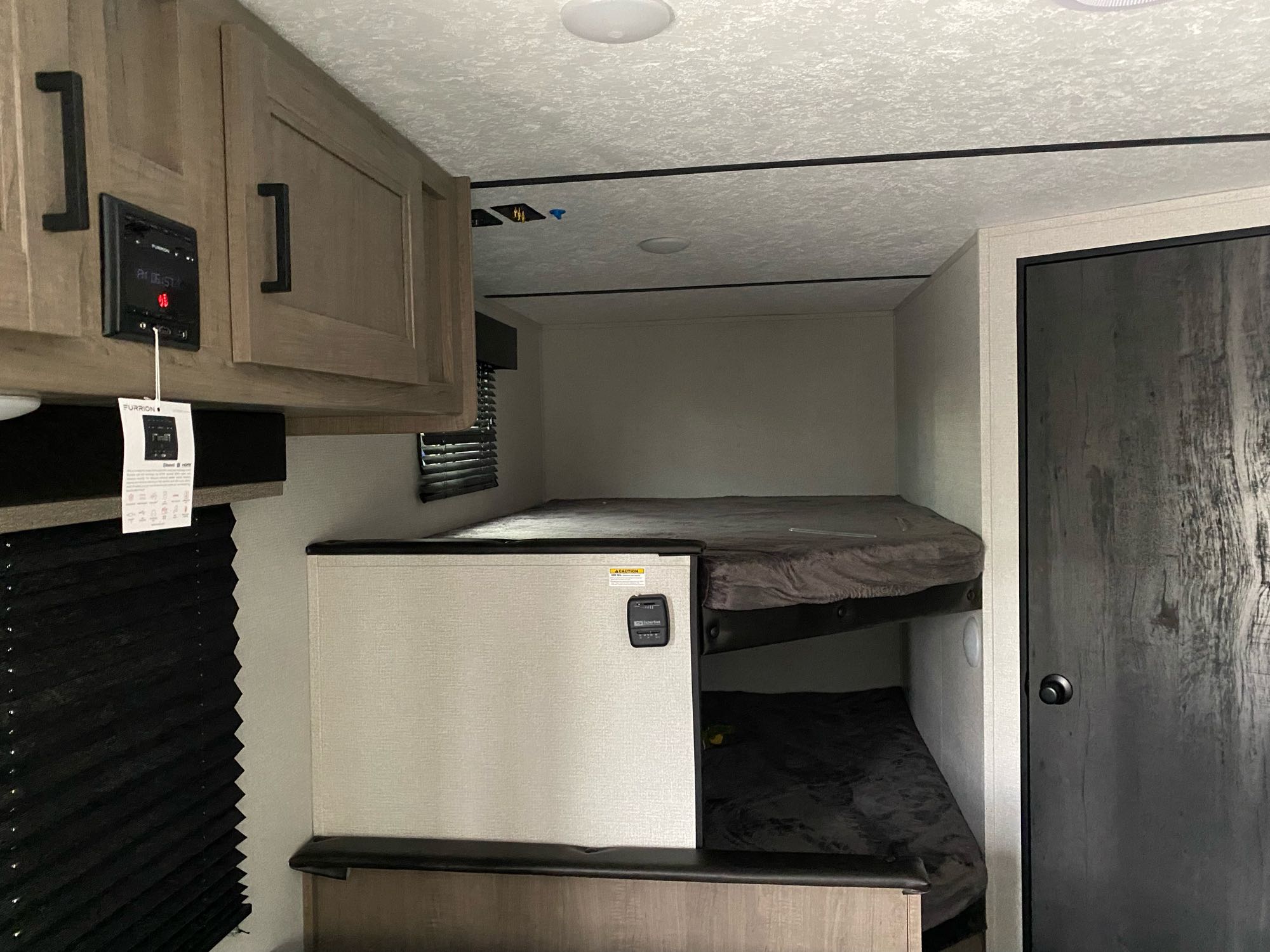 This RV rental shows a bunk bed area with two bunks, entertainment system, and cabinetry. A compact, functional interior for travel.. Keystone Hideout 2021