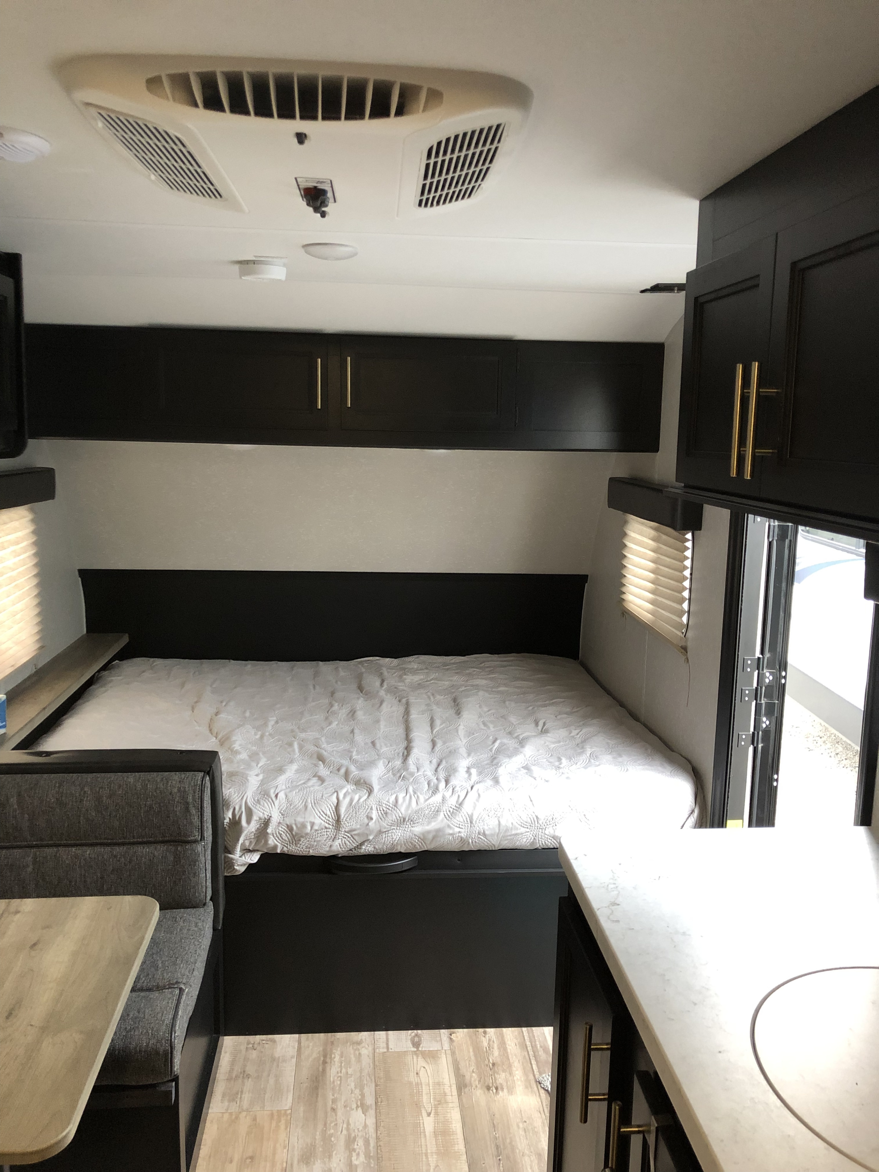 Well-designed RV rental interior: bed with storage above, small kitchen, and dinette. Light wood-look floor.. Forest River Wolf Pup 2021