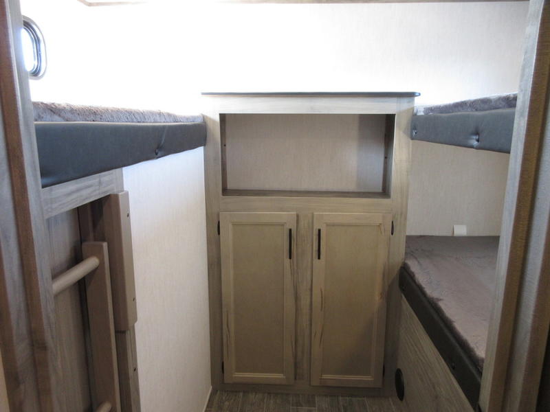 Inside an RV rental: a cozy sleeping space with multiple bunk beds and a central storage cabinet, perfect for trips.. Forest River 30DBH-L 2021