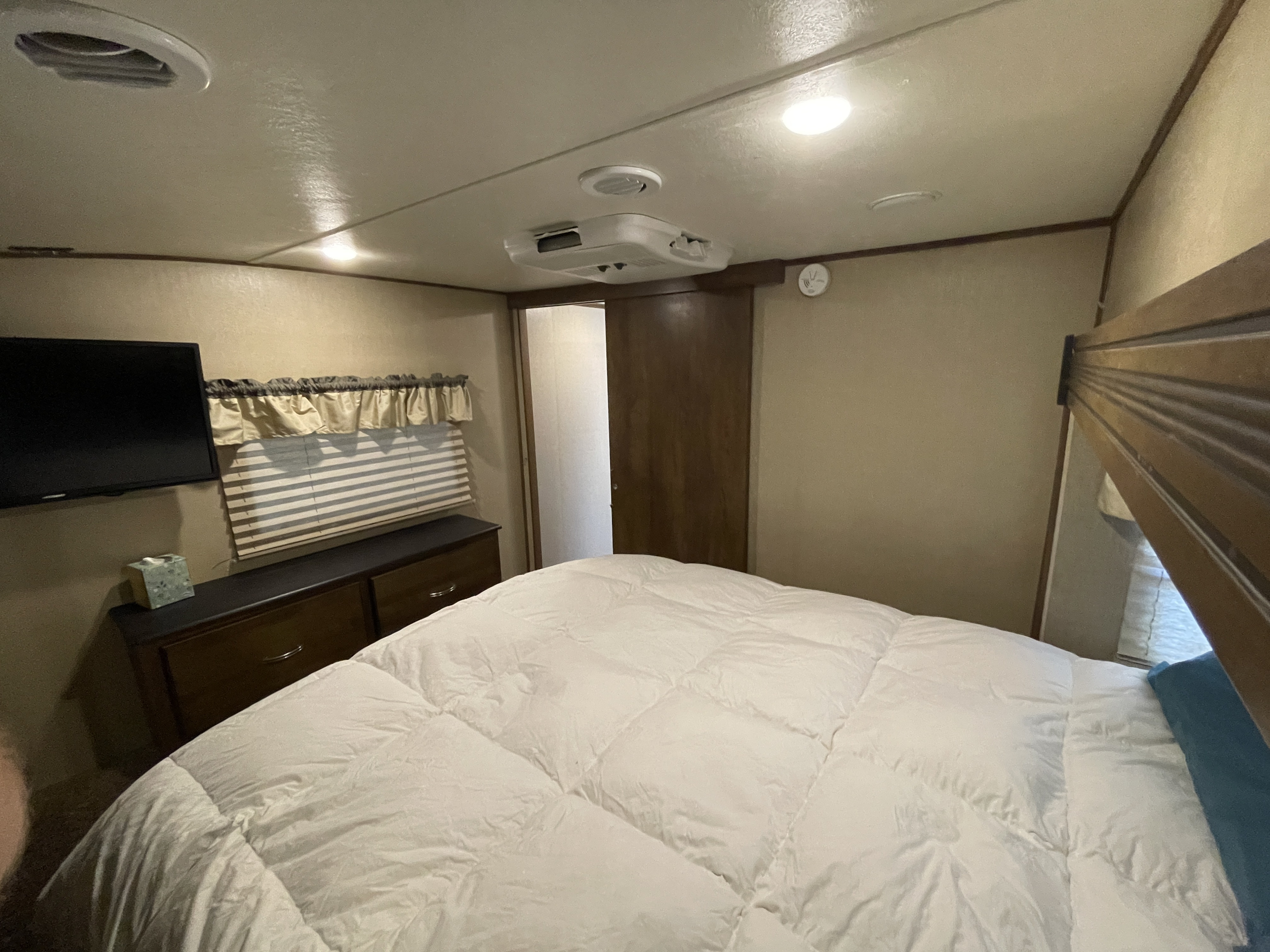 Cozy RV rental bedroom with a bed, TV, dresser, and ceiling AC unit, providing a comfortable space for travel.. Forest River Coachmen Chaparral 2017