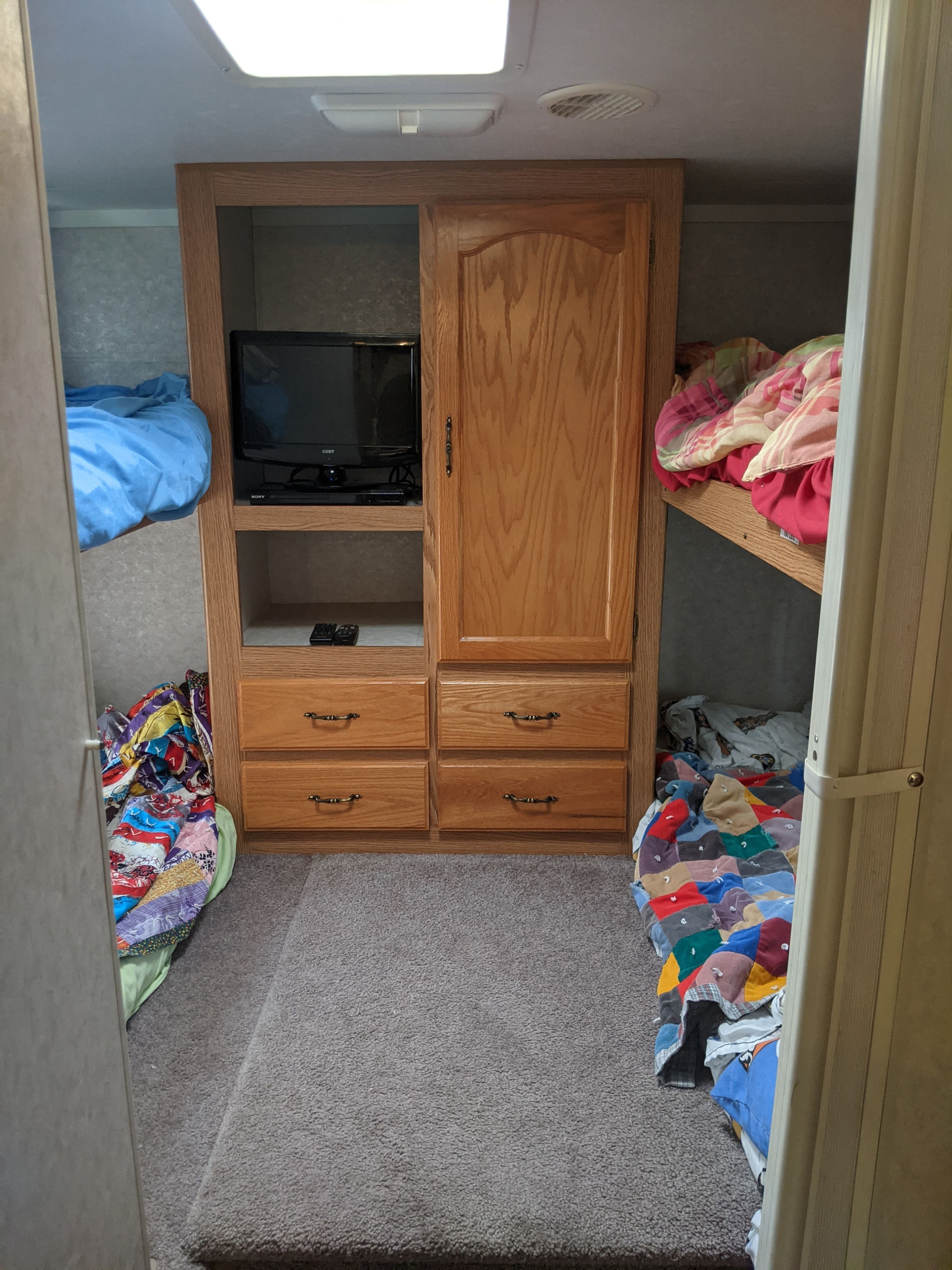 RV rental bunk room: featuring twin bunk beds, a central media cabinet with TV, and ample storage.. K-Z Manufacturing Sportsmen 2003