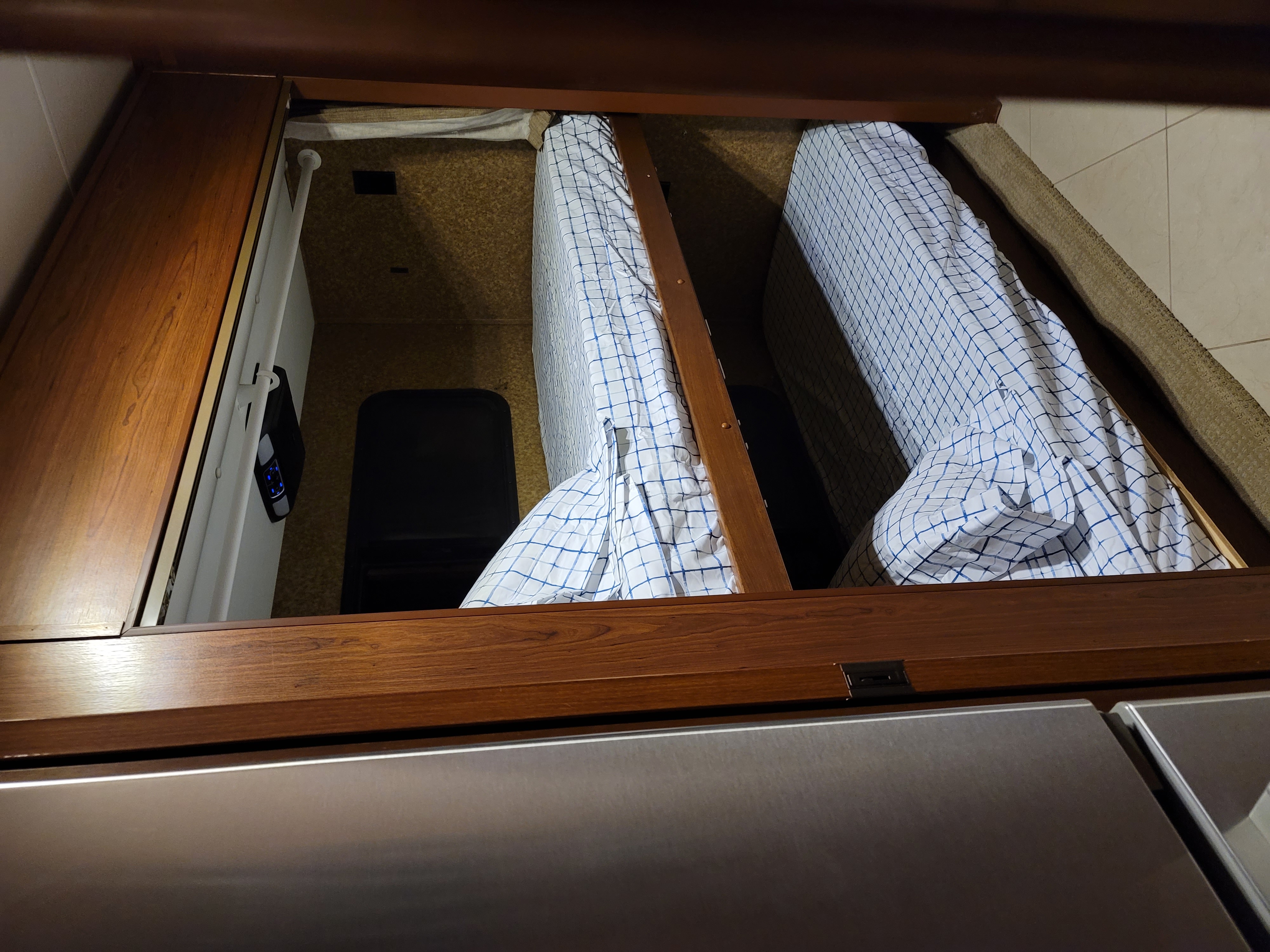 RV rental interior: Overhead view of cozy bunk beds with checkered sheets, built-in storage, and the top of a refrigerator.. Forest River Other 2014
