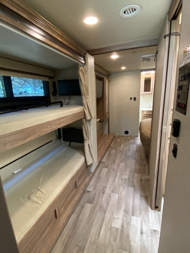 Explore this RV rental's interior: bunk beds, wood flooring, and a clear path to the rear bathroom.. Jayco Precept 2019