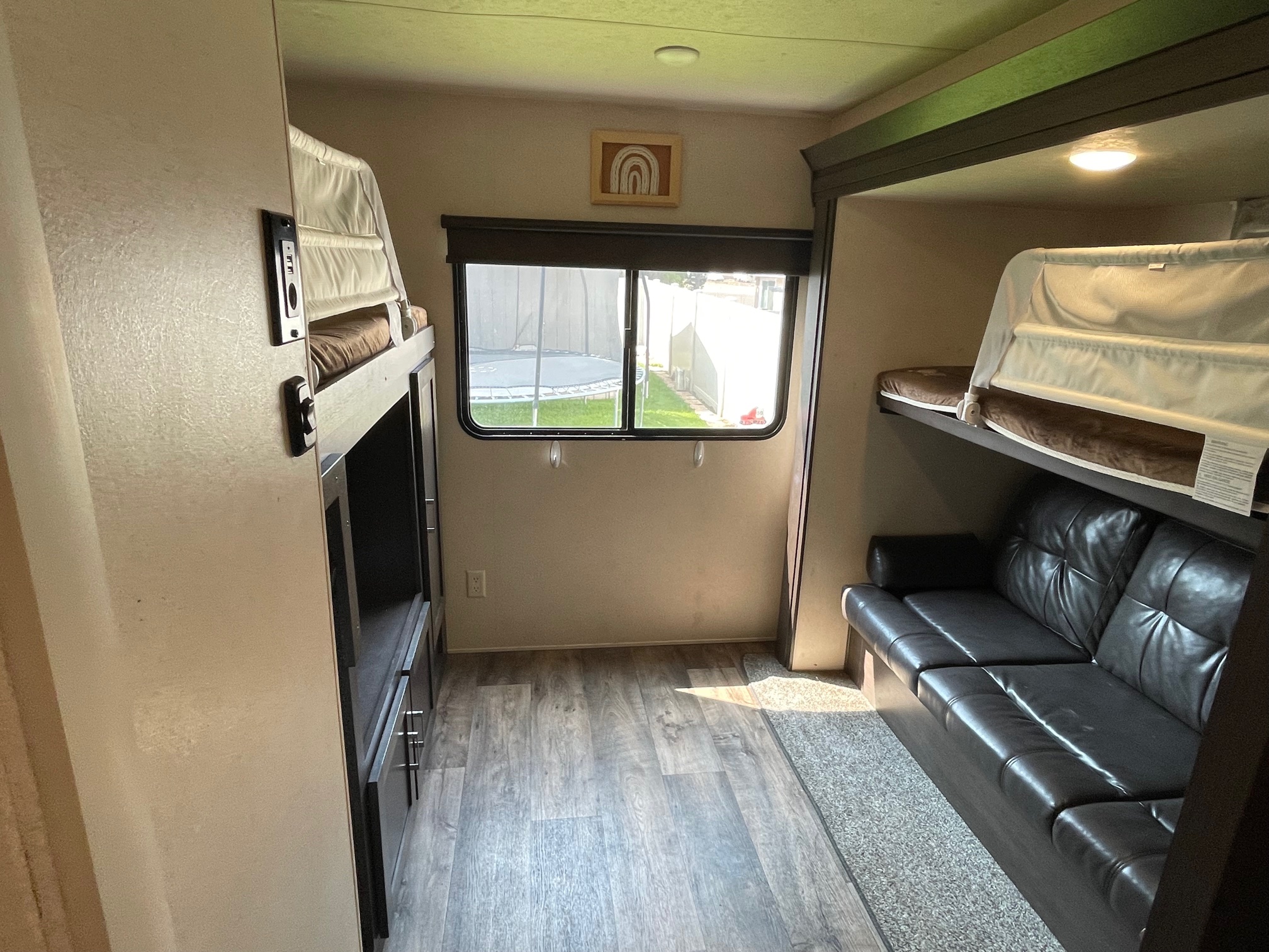 RV rental bunkhouse interior: dual bunk beds, comfy sofa, window, and wood floors for your travel comfort.. Forest River Wildwood 2019