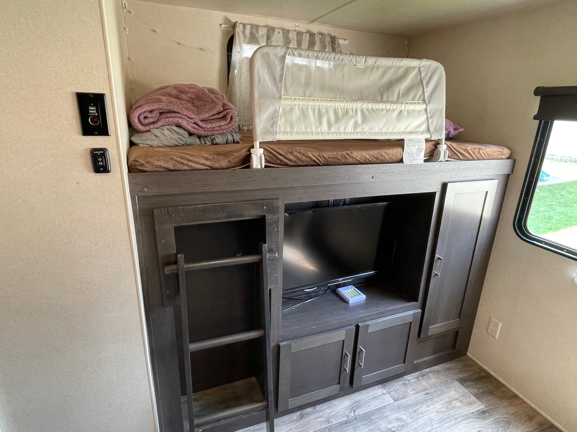 RV rental interior: bunk beds with safety rail, TV, and storage. Perfect for family trips in a camper.. Forest River Wildwood 2019