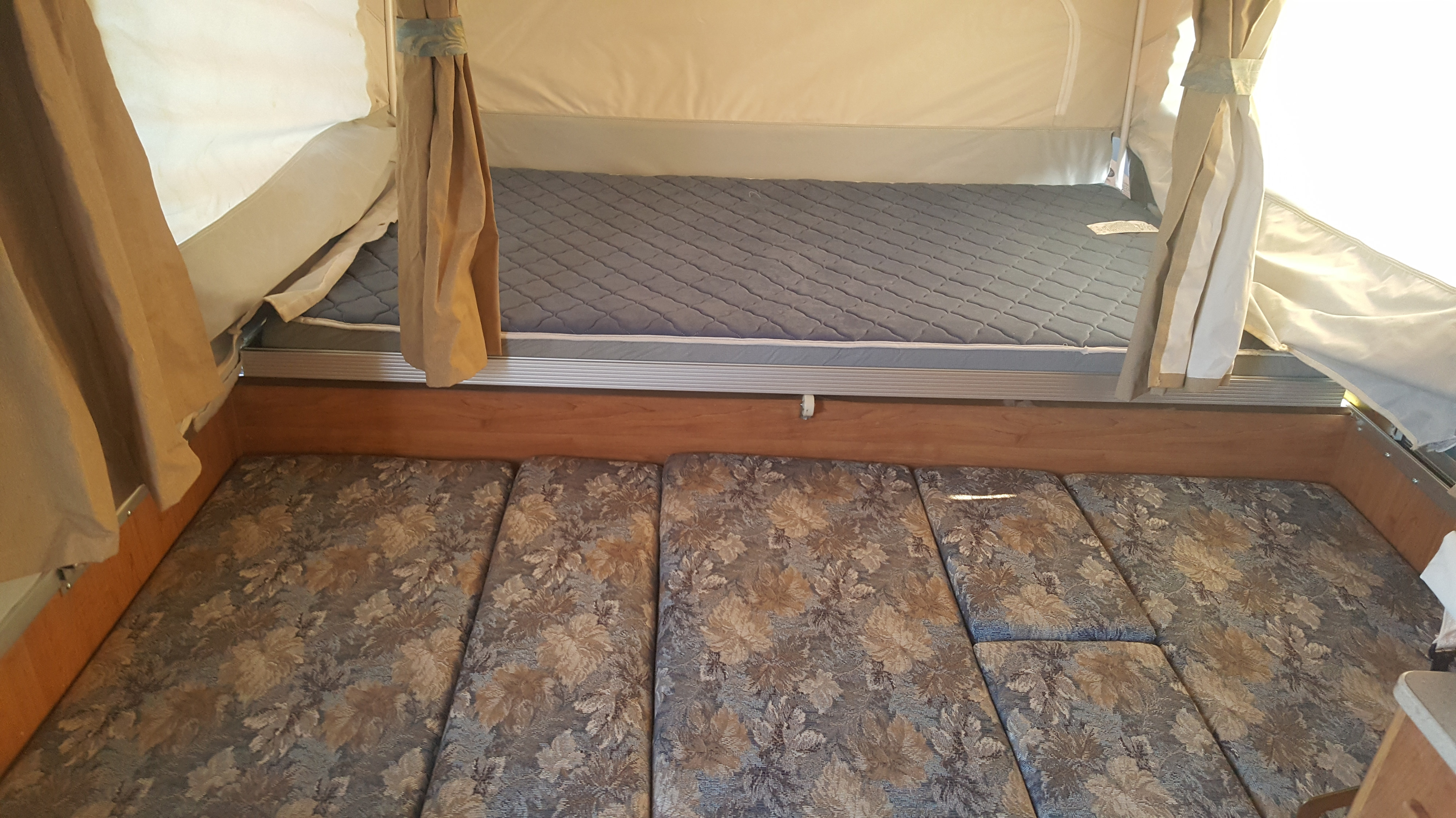 Pop-up camper rv rental interior: view of extendable bed with grey mattress & convertible dinette cushions.. Forest River Flagstaff 2008