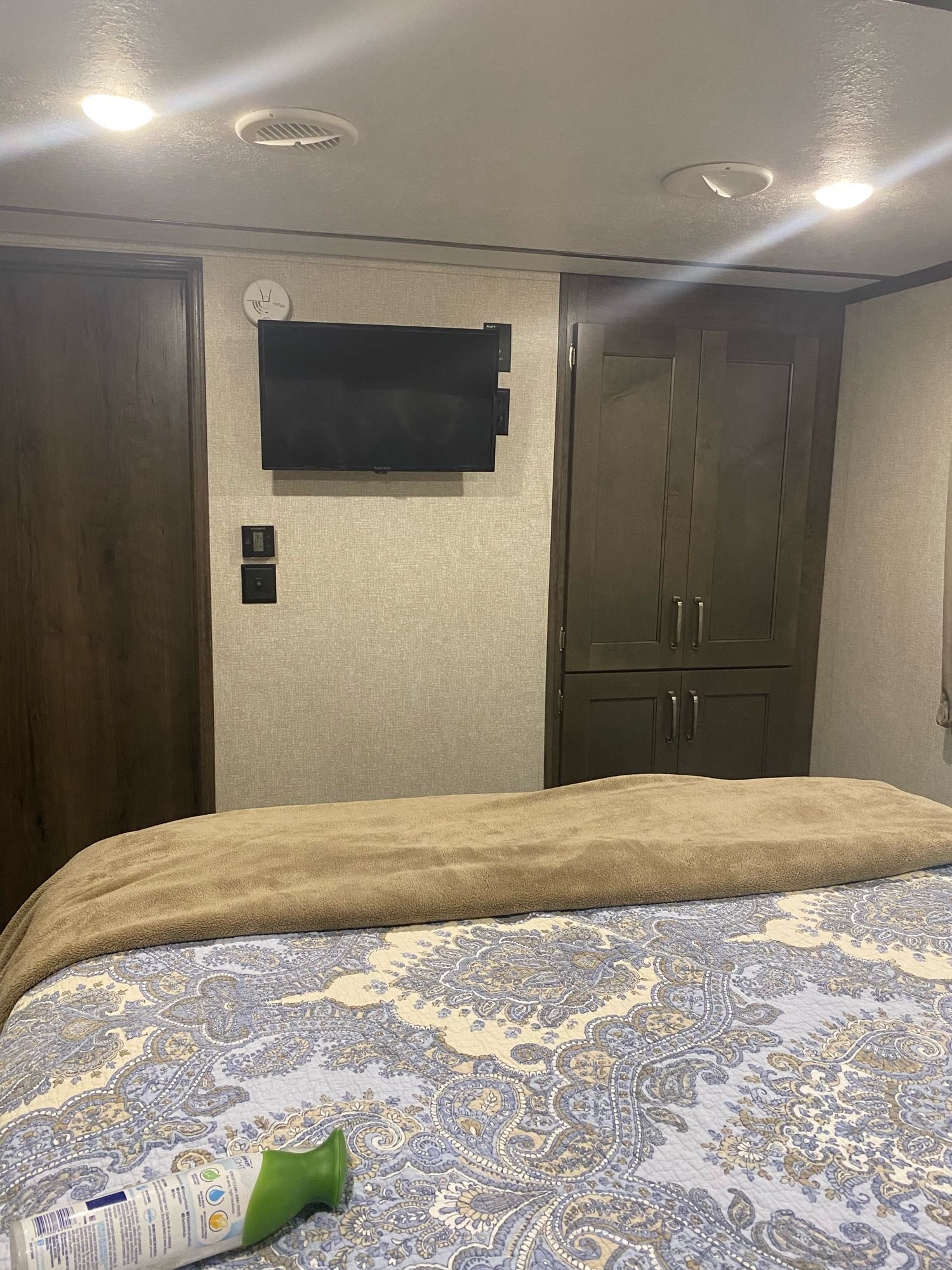 Inside an RV rental bedroom, featuring a comfortable bed, wall-mounted TV, built-in closet, and ceiling amenities.. Keystone Montana High Country 2020