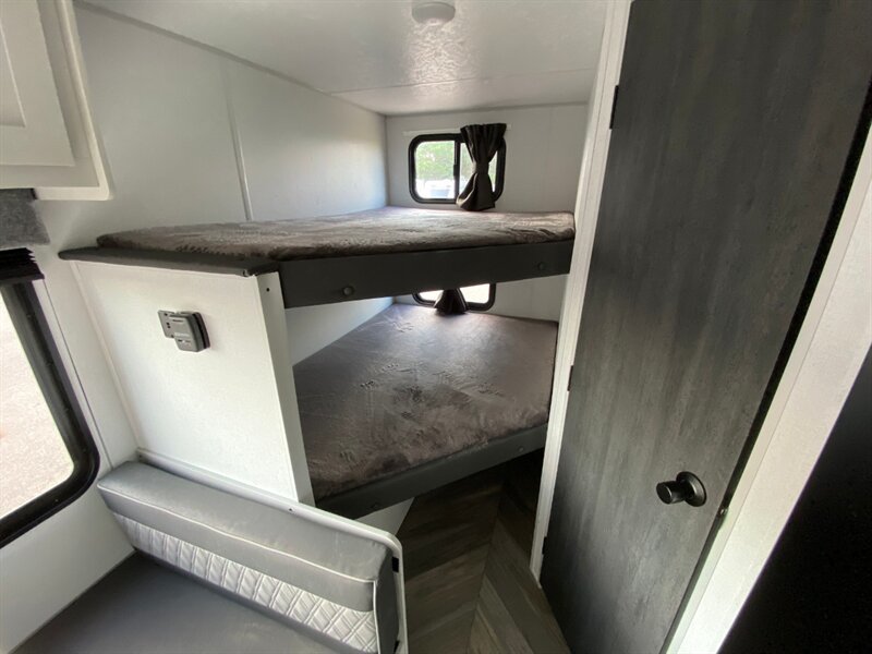 Cozy RV rental interior with bunk beds & dinette seating, perfect for families. Enjoy compact travel comfort.. Forest River Salem 2021