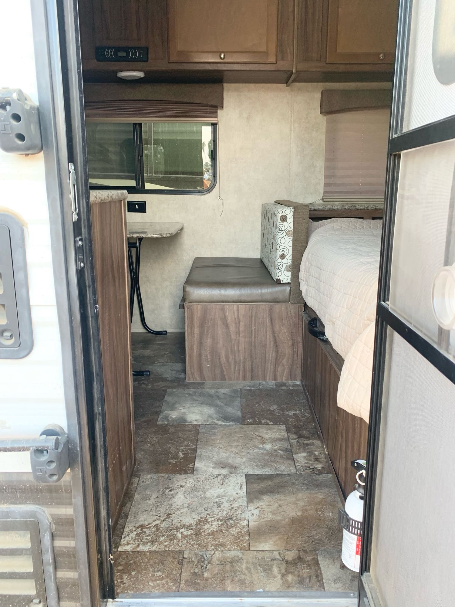RV rental interior: view of compact dinette, window, and cozy bed. Fire extinguisher visible.. Coachmen Clipper 2015