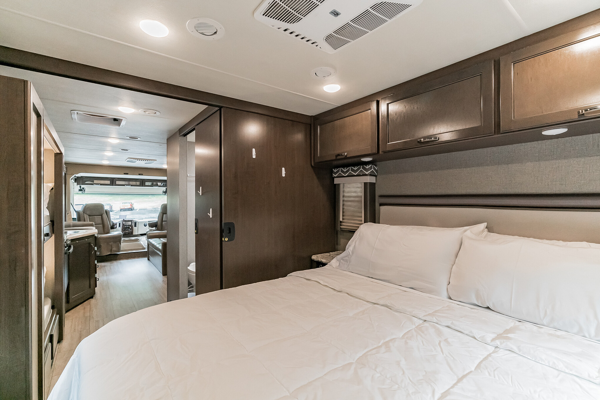 Inside a comfortable RV rental: A view from the inviting bedroom to the spacious front cockpit and driver's area.. Thor Motor Coach Freedom Elite 2020