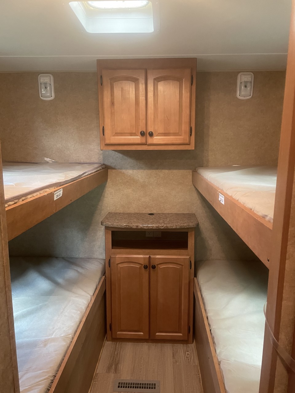 Cozy RV rental bunkhouse featuring two sets of bunks, ample storage cabinets, and bright lighting for comfortable travel.. Heartland North Country Lakeside 2011