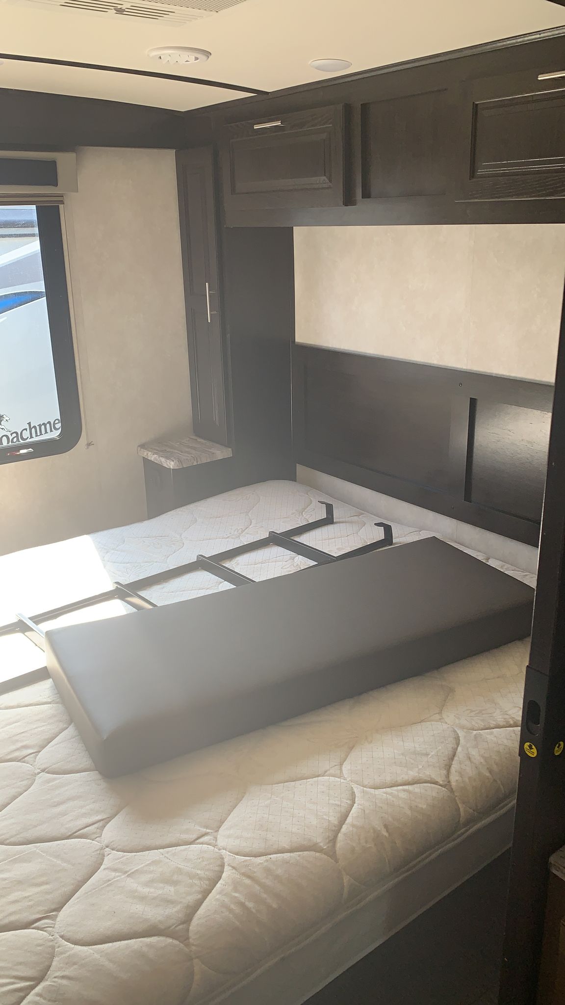 Cozy rv rental bedroom features a comfy quilted mattress, fold-out bed mechanism, storage, and window view for travel.. Forest River Other 2020