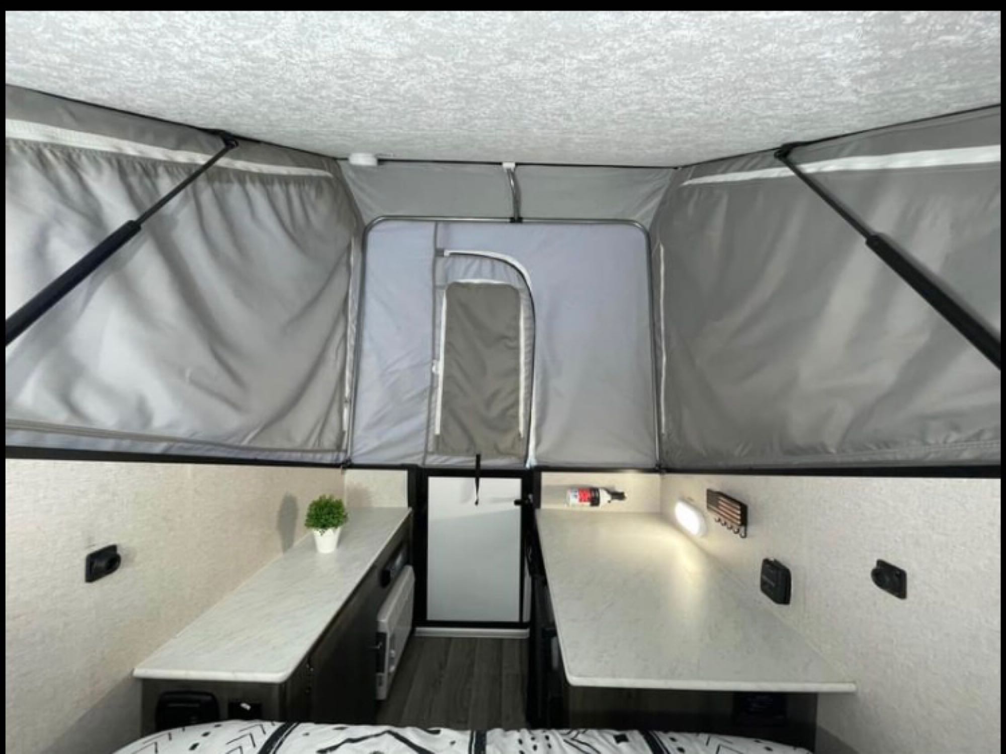 This RV rental shows a pop-up trailer interior: high tent ceiling, two countertop areas, and a central aisle.. Coachmen Viking 2020