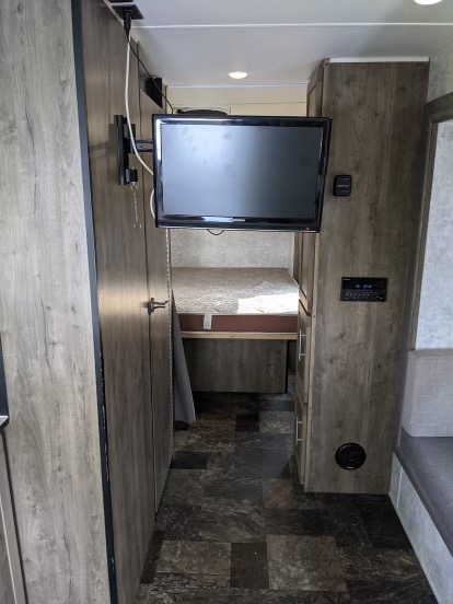Explore this RV rental's cozy interior, featuring a mounted TV, stereo, bunk bed, and dark wood-grain finishes.. ProLite Xtreme 2019