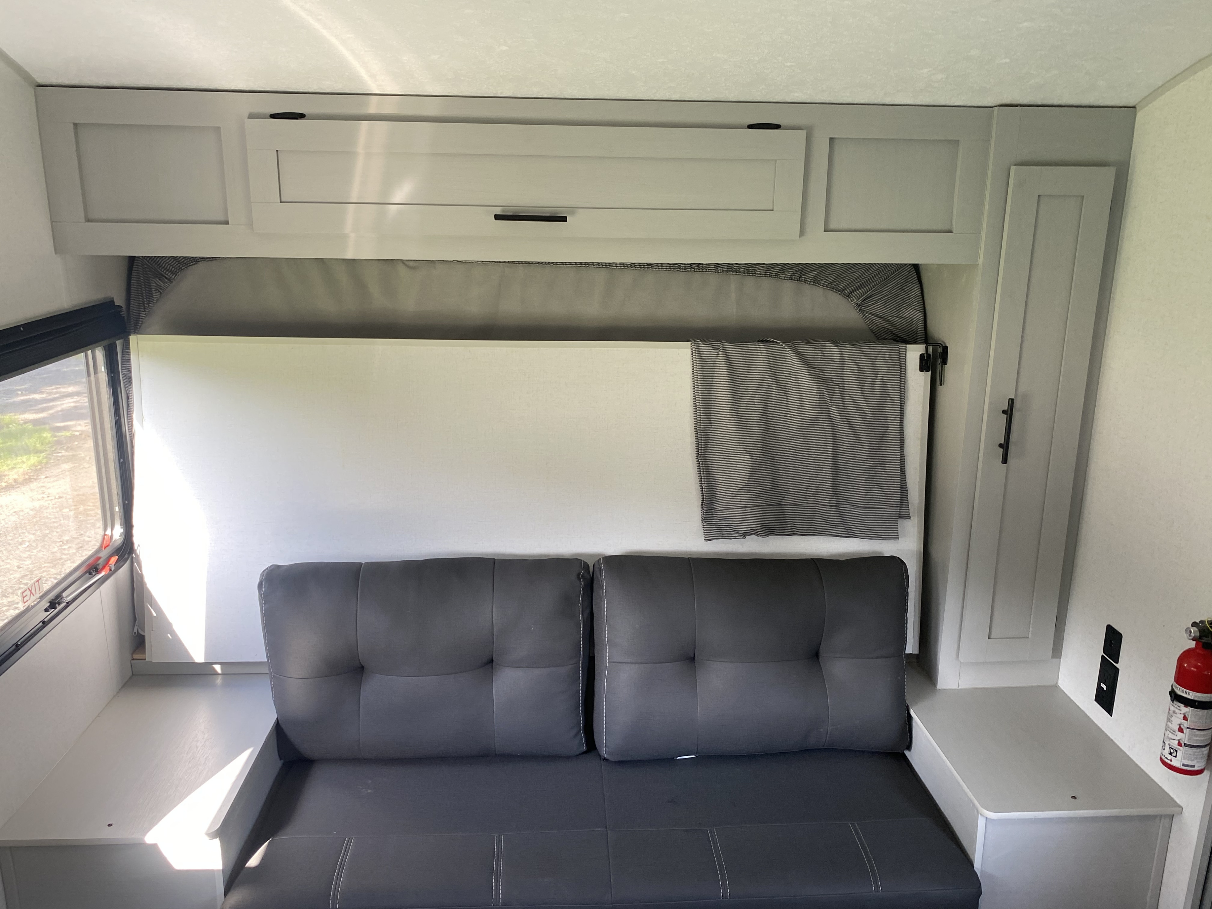 RV rental's bright interior features a gray convertible sofa, an overhead bunk bed, storage cabinets, and a window.. Forest River Salem 2021
