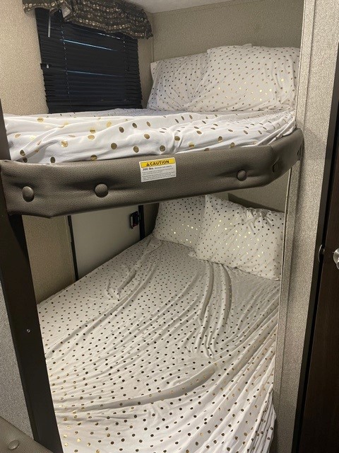 RV rental bunk beds with white and gold polka dot bedding offer a cozy sleeping area.. Keystone Springdale 2020