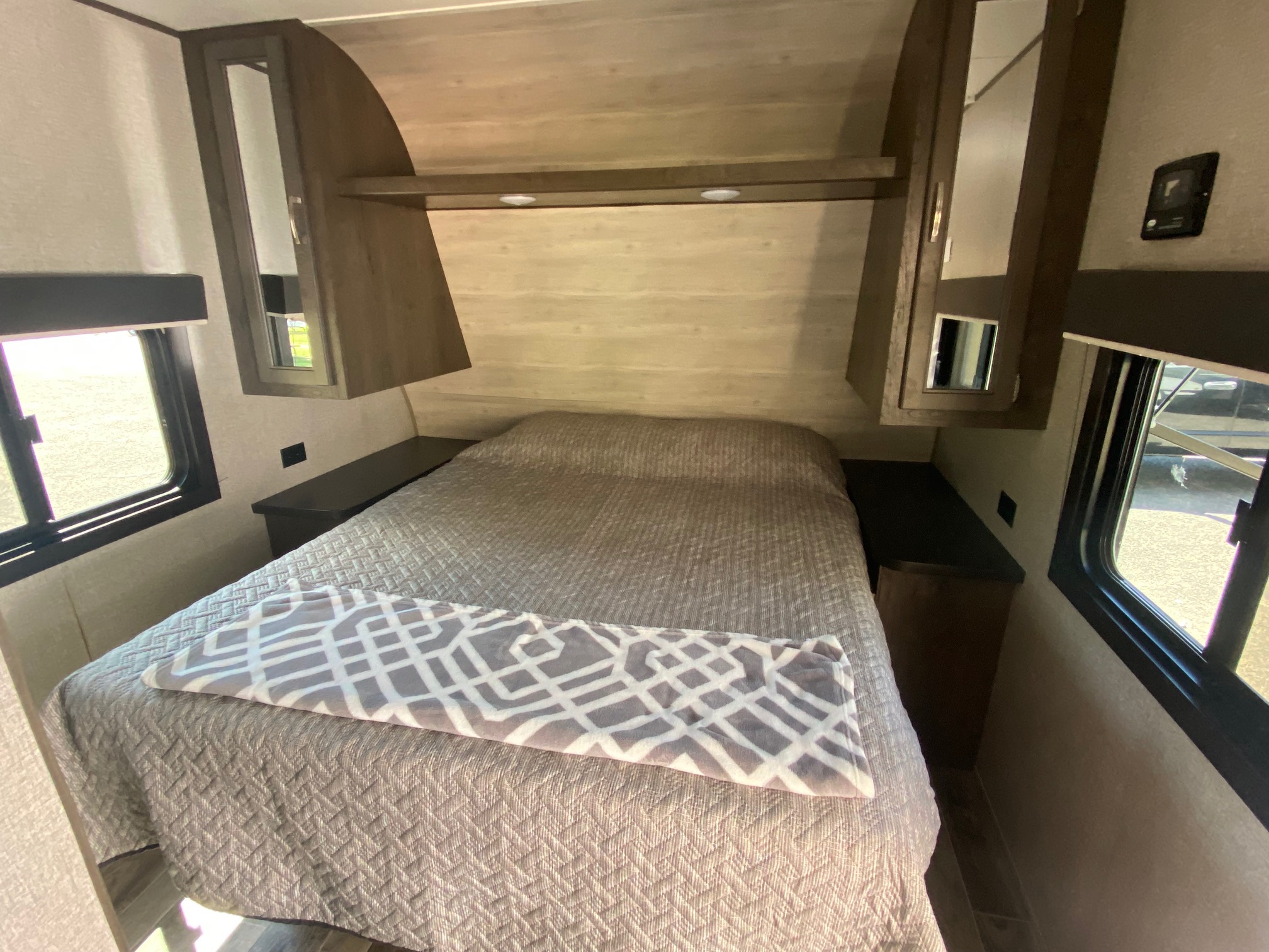 Cozy RV rental bedroom featuring a comfy bed with quilt, overhead storage, and windows, ideal for travel.. Jayco Jay Flight SLX Rocky Mountain Edition 2021