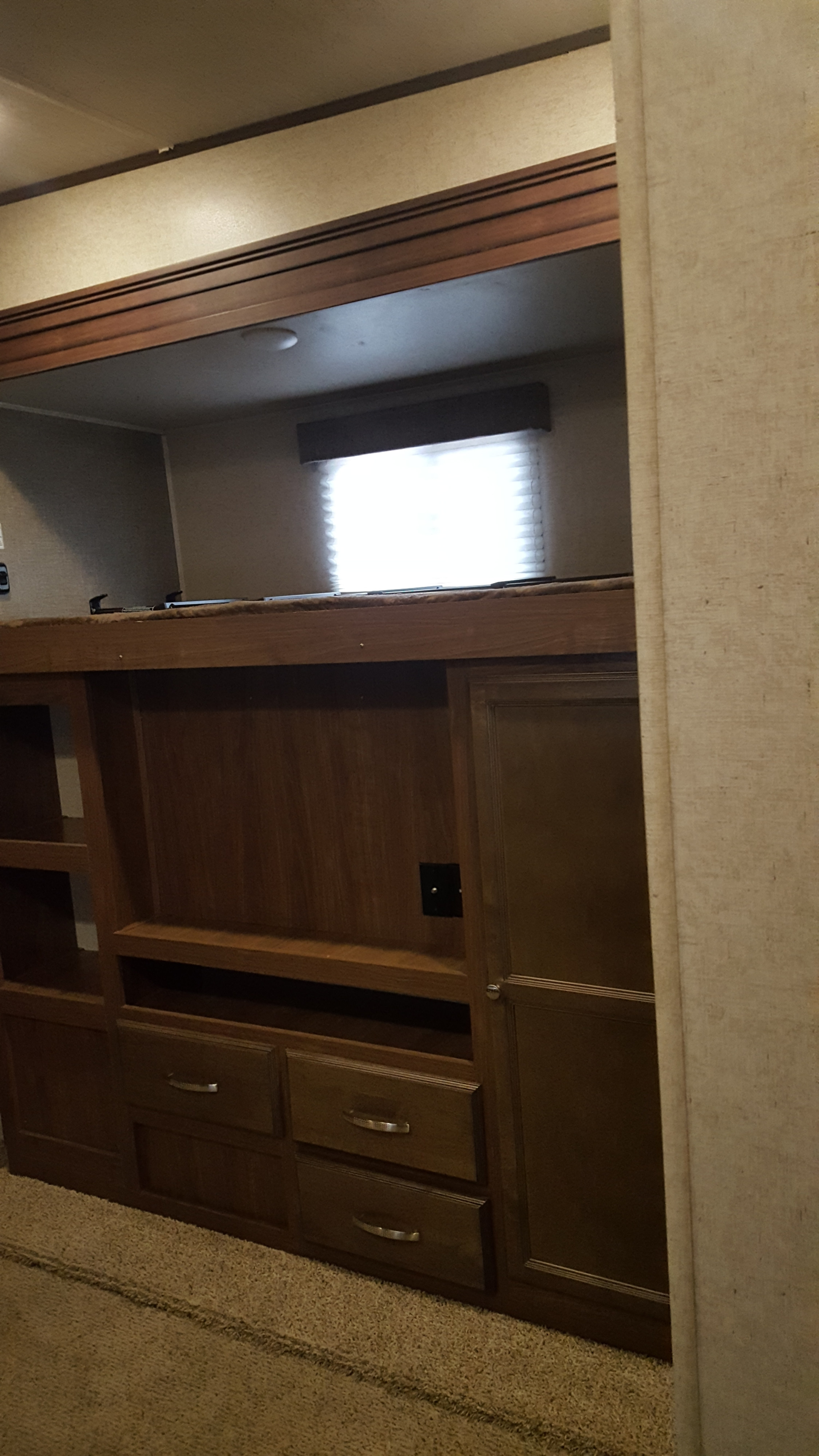 RV rental bunk area: wood bunk, storage cabinets, window with blinds. Cozy camper interior ready for adventure.. Heartland Elkridge 2017
