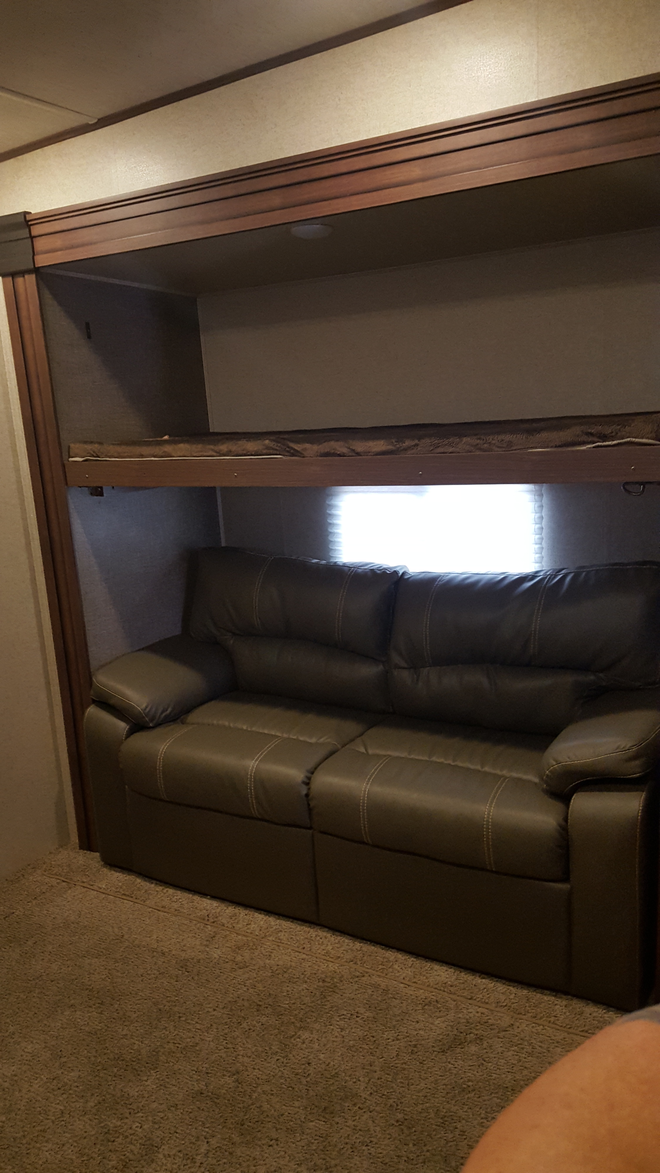 RV rental interior featuring a comfortable sofa below a convenient bunk bed, ideal for compact living spaces.. Heartland Elkridge 2017