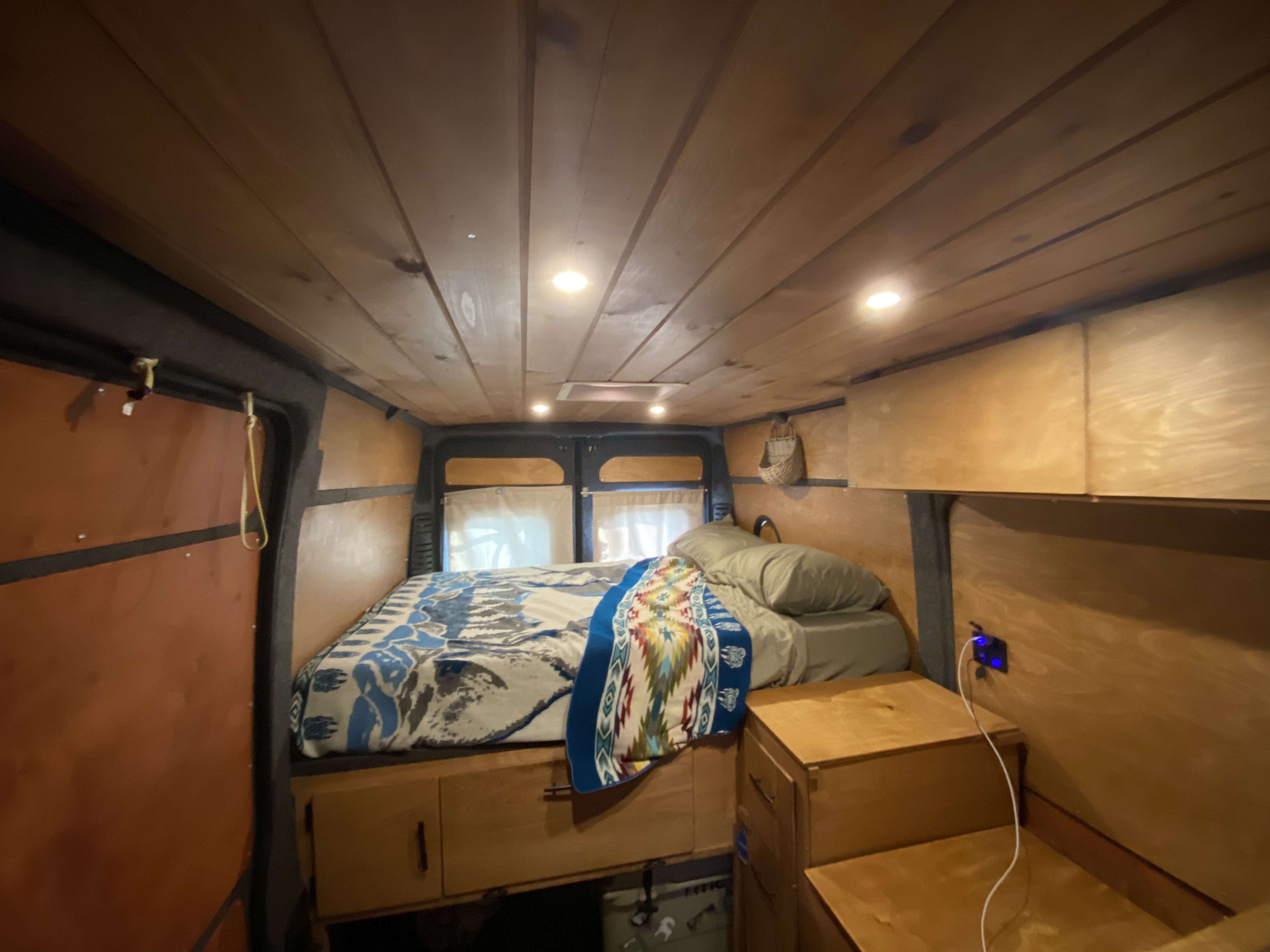 Experience comfort in this RV rental! Features a cozy bed, warm wood interior, and smart storage solutions.. Dodge 1500 2017