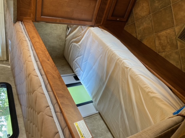 RV rental sleeping area showing two mattresses, wooden divider, and overhead cabinets.. Other Passport 2012