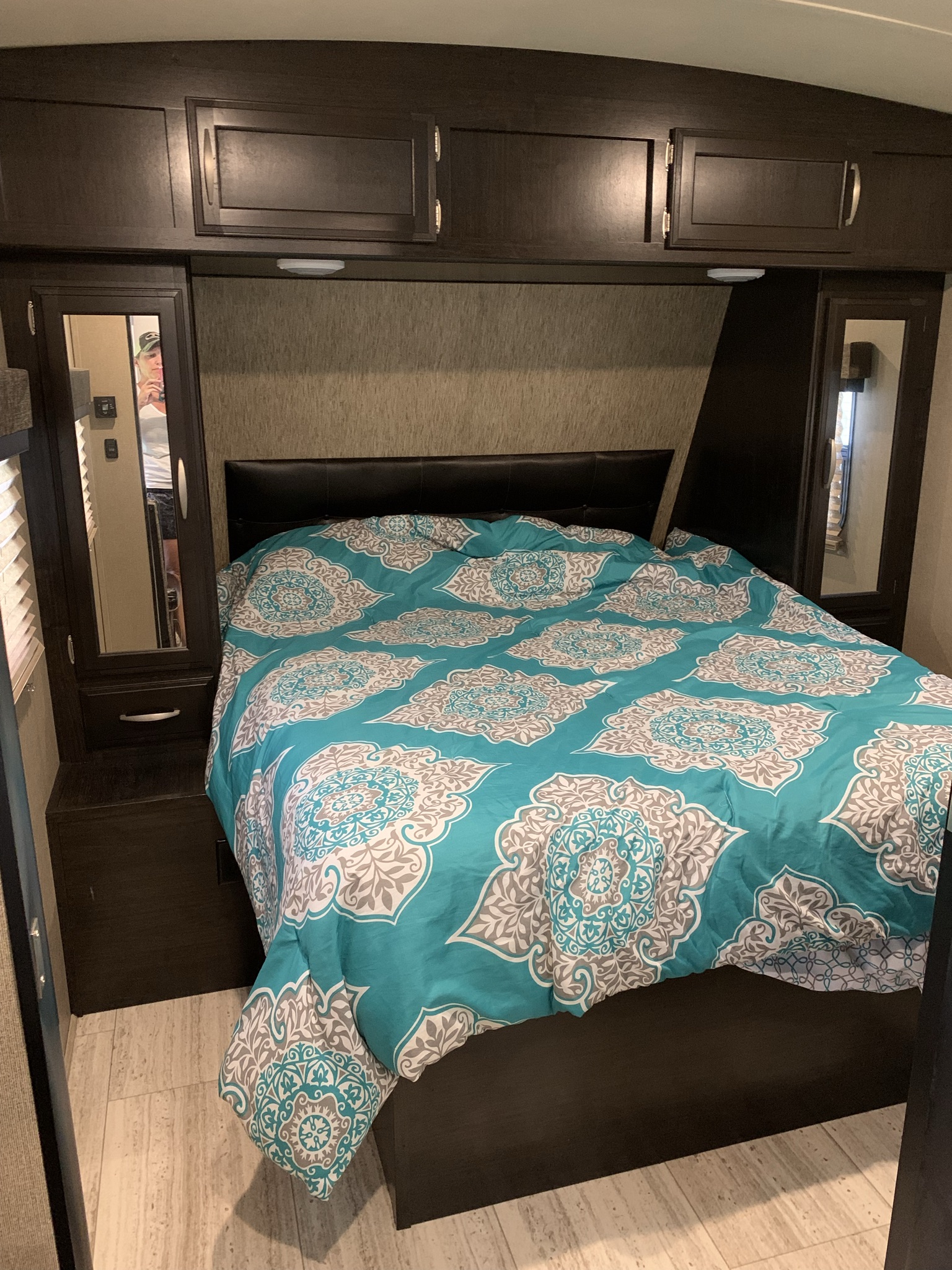 Cozy RV rental bedroom featuring a patterned comforter, built-in storage, and mirrored cabinets.. Grand Design Other 2016