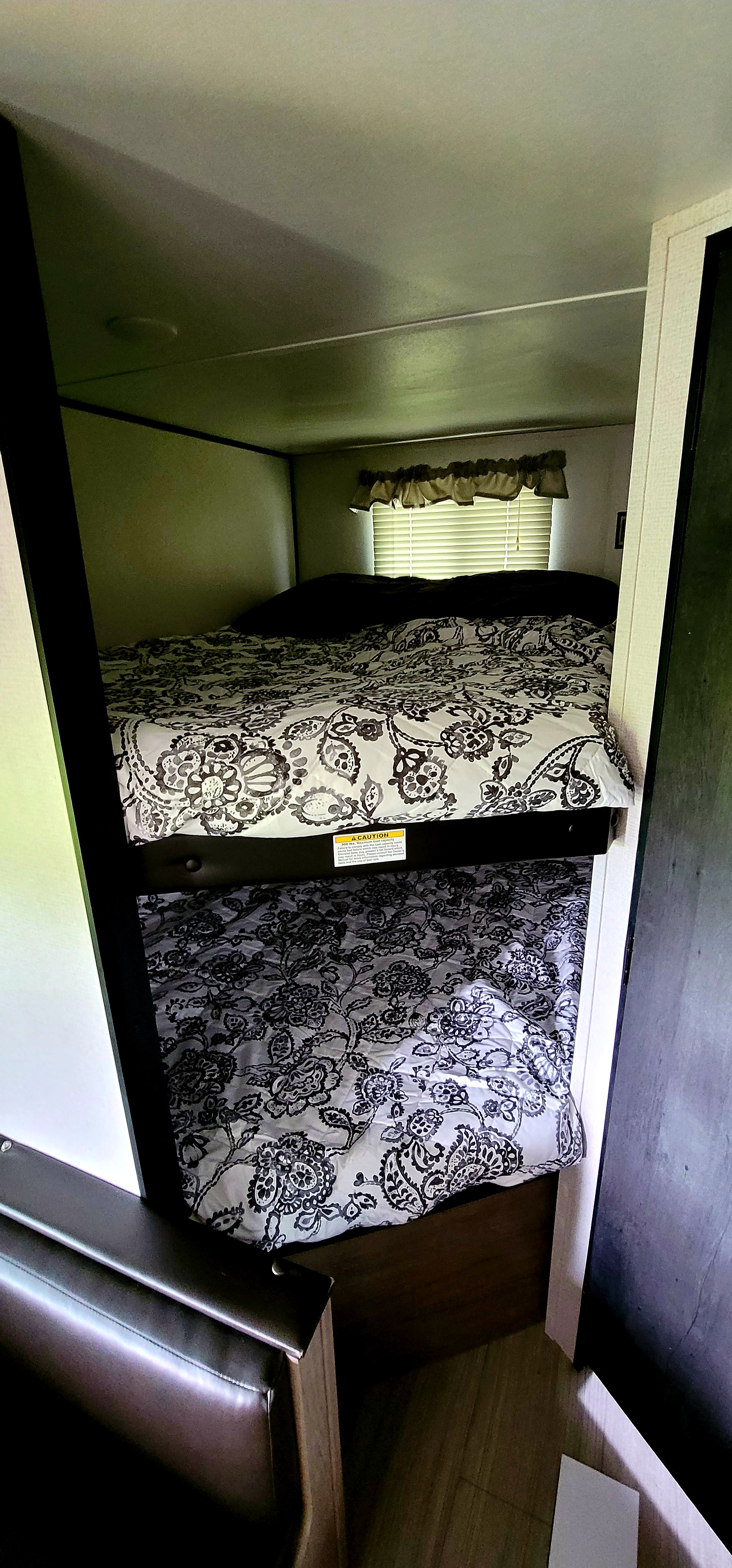 Inside an RV rental, two bunk beds with black and white patterned bedding, ideal for family trips.. Keystone Hideout 2021