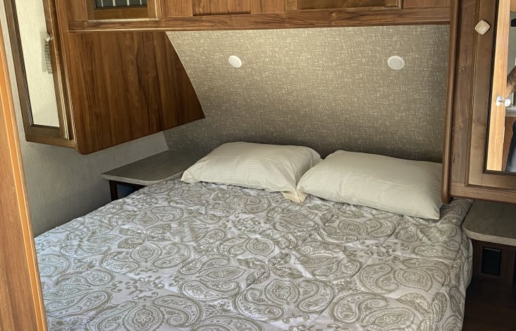 Comfortable RV rental bedroom featuring a bed with paisley linens, bedside shelves, and overhead cabinets for travel comfort.. Heartland Other 2018