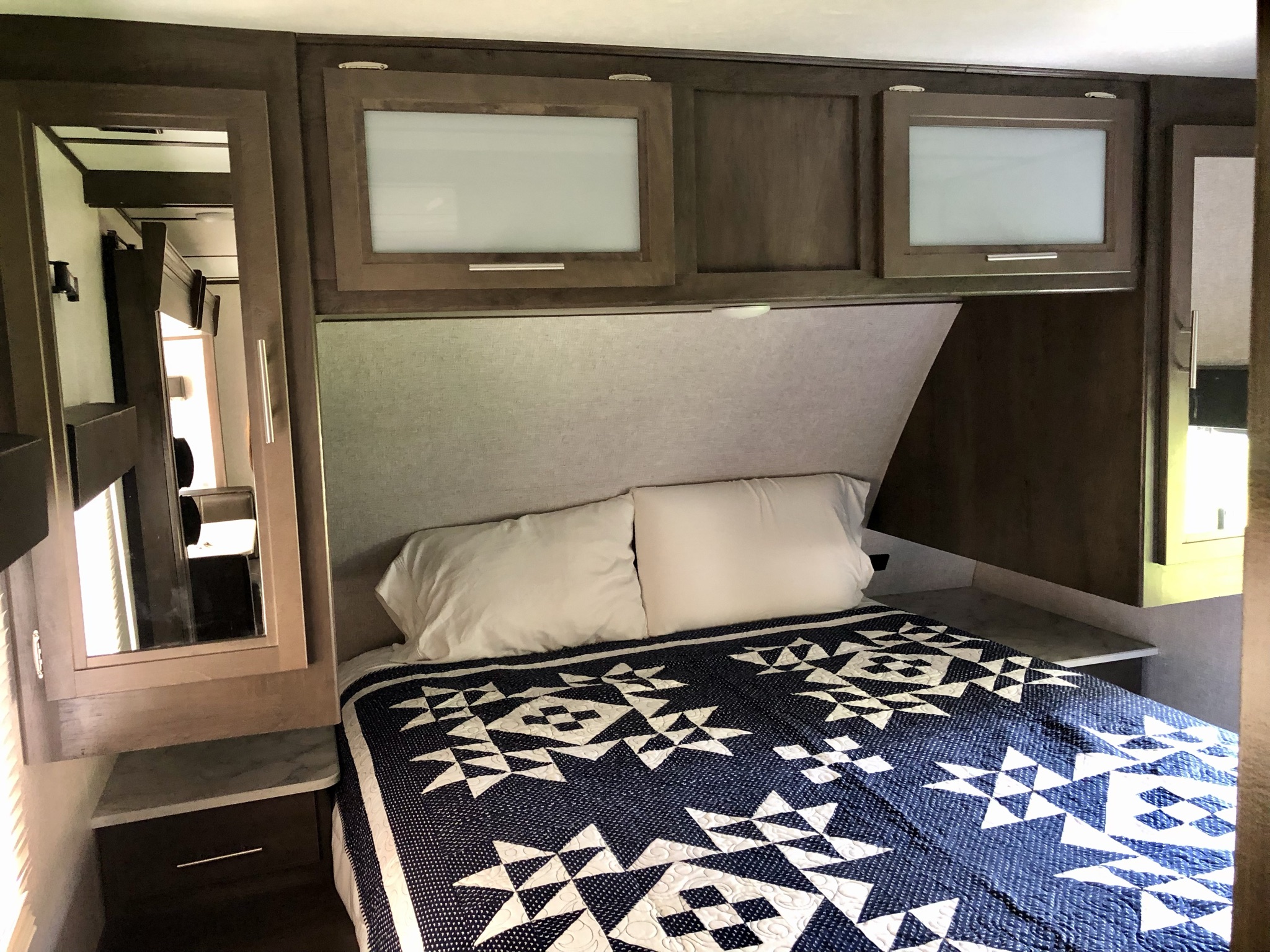 RV rental bedroom with bed, quilt, overhead cabinets & nightstands. A comfy interior for your travels.. Coleman Other 2021