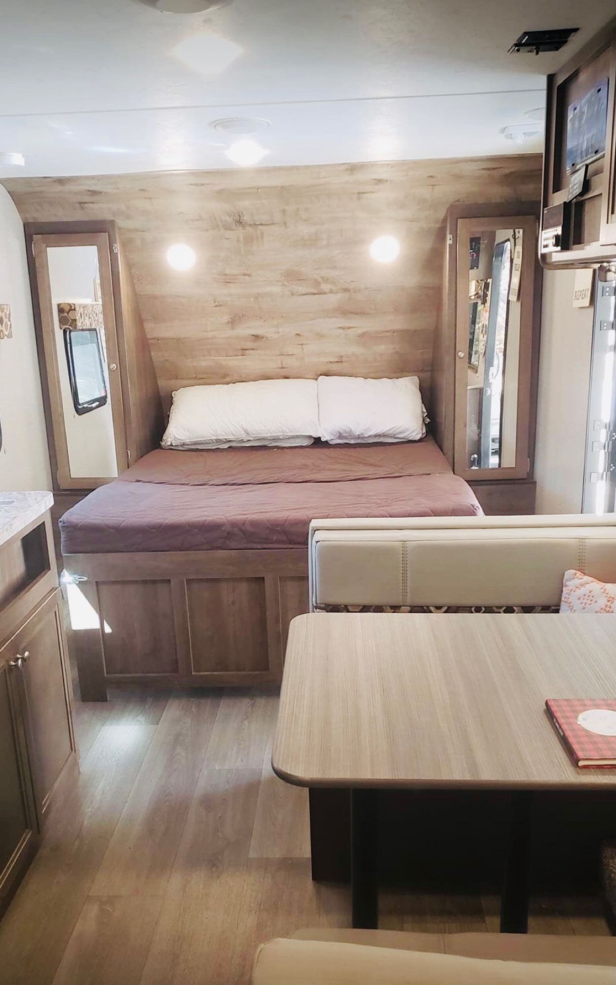 RV rental interior: A cozy bedroom with wood walls and bed, adjacent to a dining area with table and bench.. Dutchmen Other 2018