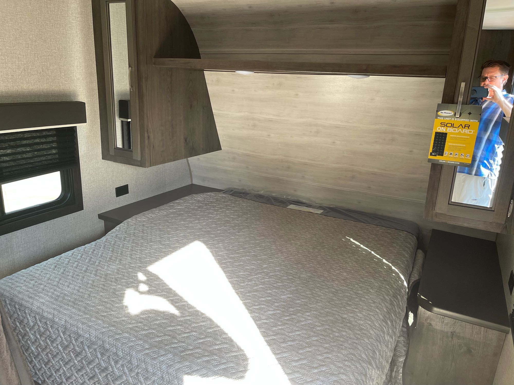 Explore this RV rental's bedroom: Features a comfy bed, overhead cabinets, and a window, reflecting solar power readiness.. Jayco Baja 2021