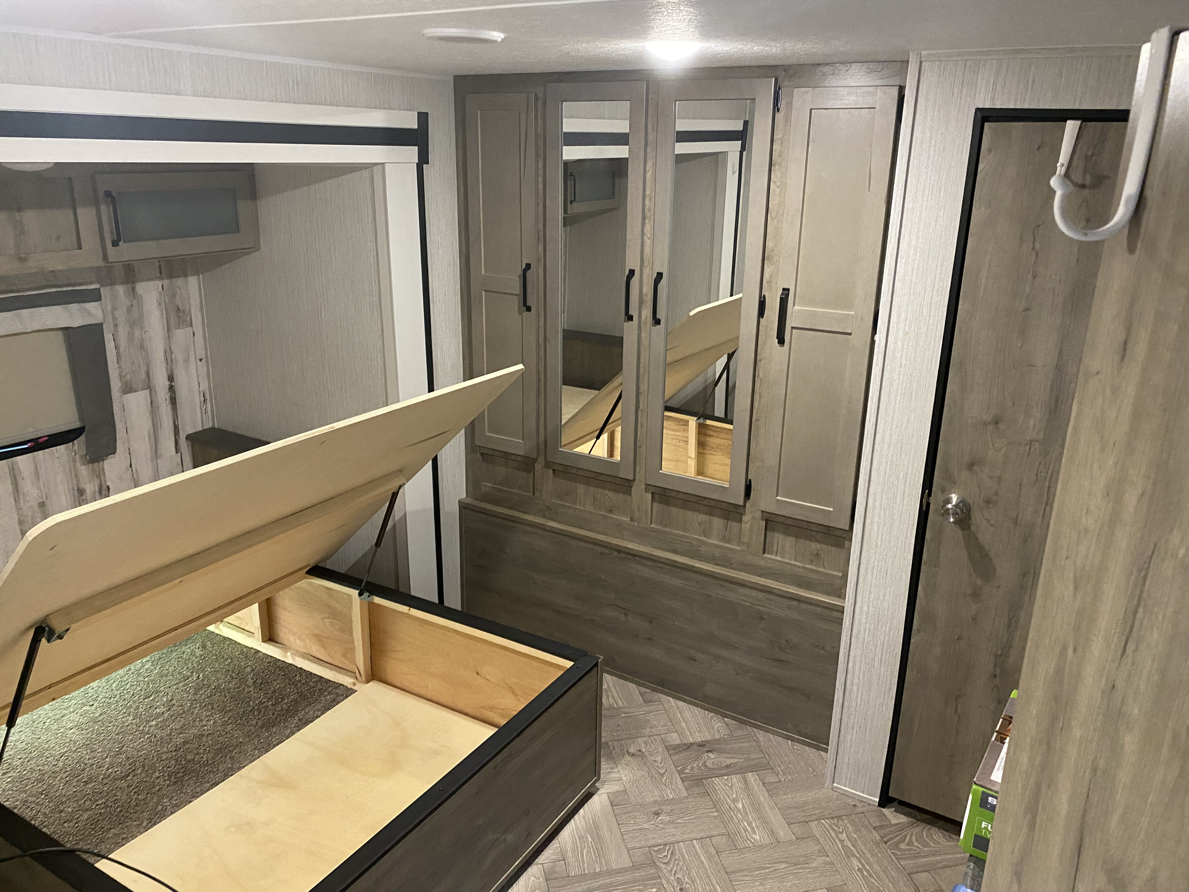 This RV rental bedroom features a lift-up bed revealing ample storage, mirrored wardrobes, and modern wood-look flooring.. Forest River Other 2021